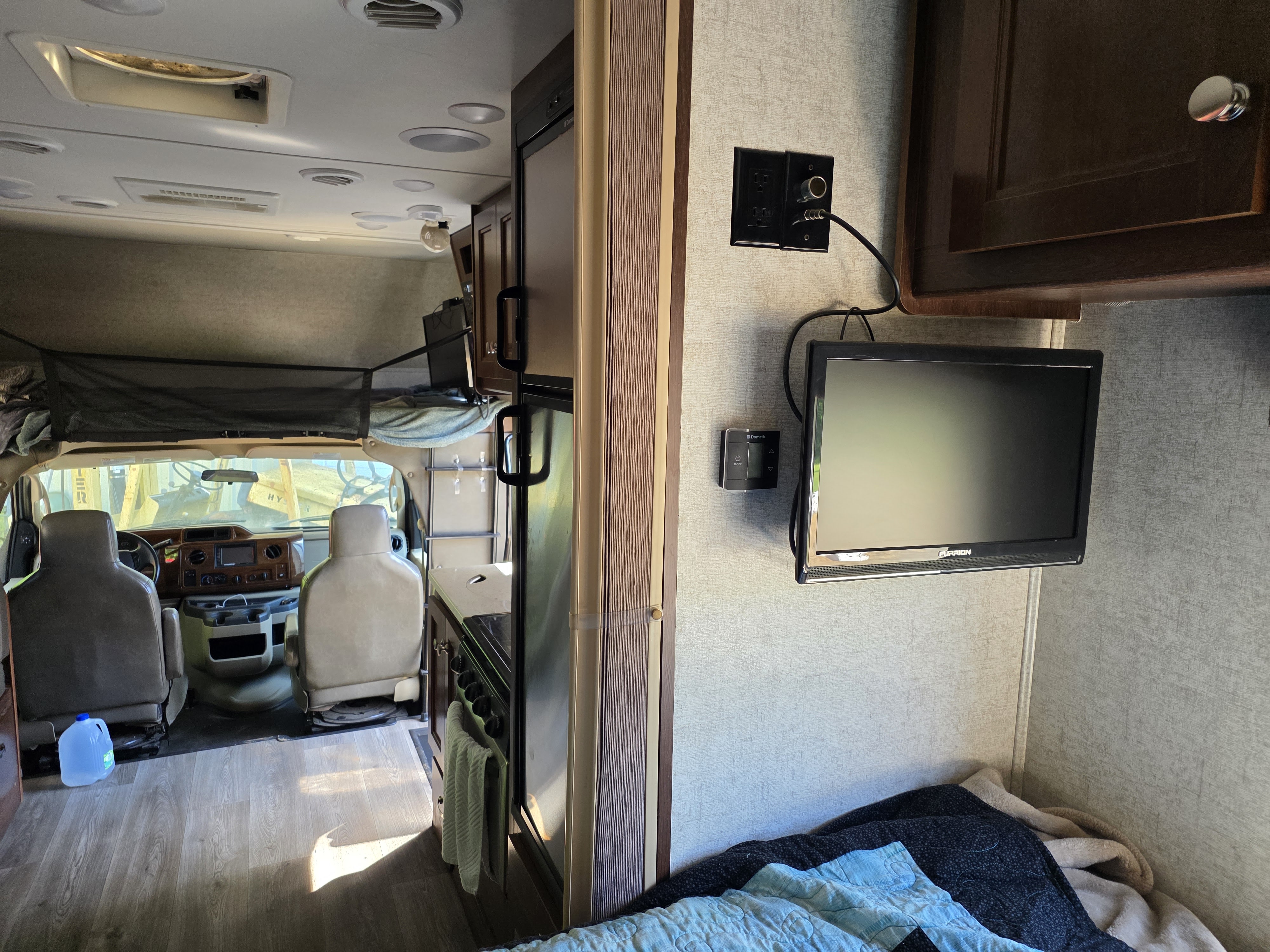 Step inside this RV rental: view from the bed area to the cockpit, featuring a mounted TV, kitchen, and overhead bunk.. Forest River Forester 2017