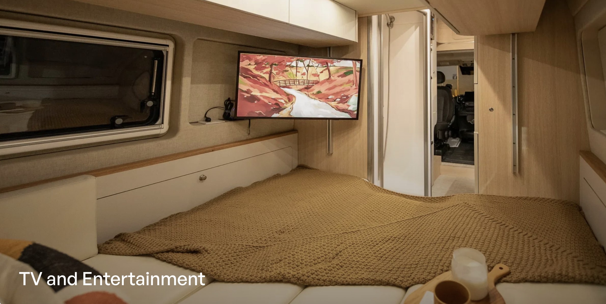 This cozy rv rental bedroom features a wall-mounted TV for entertainment above a comfortable bed and window.. Noovo Noovo Plus LB 2026