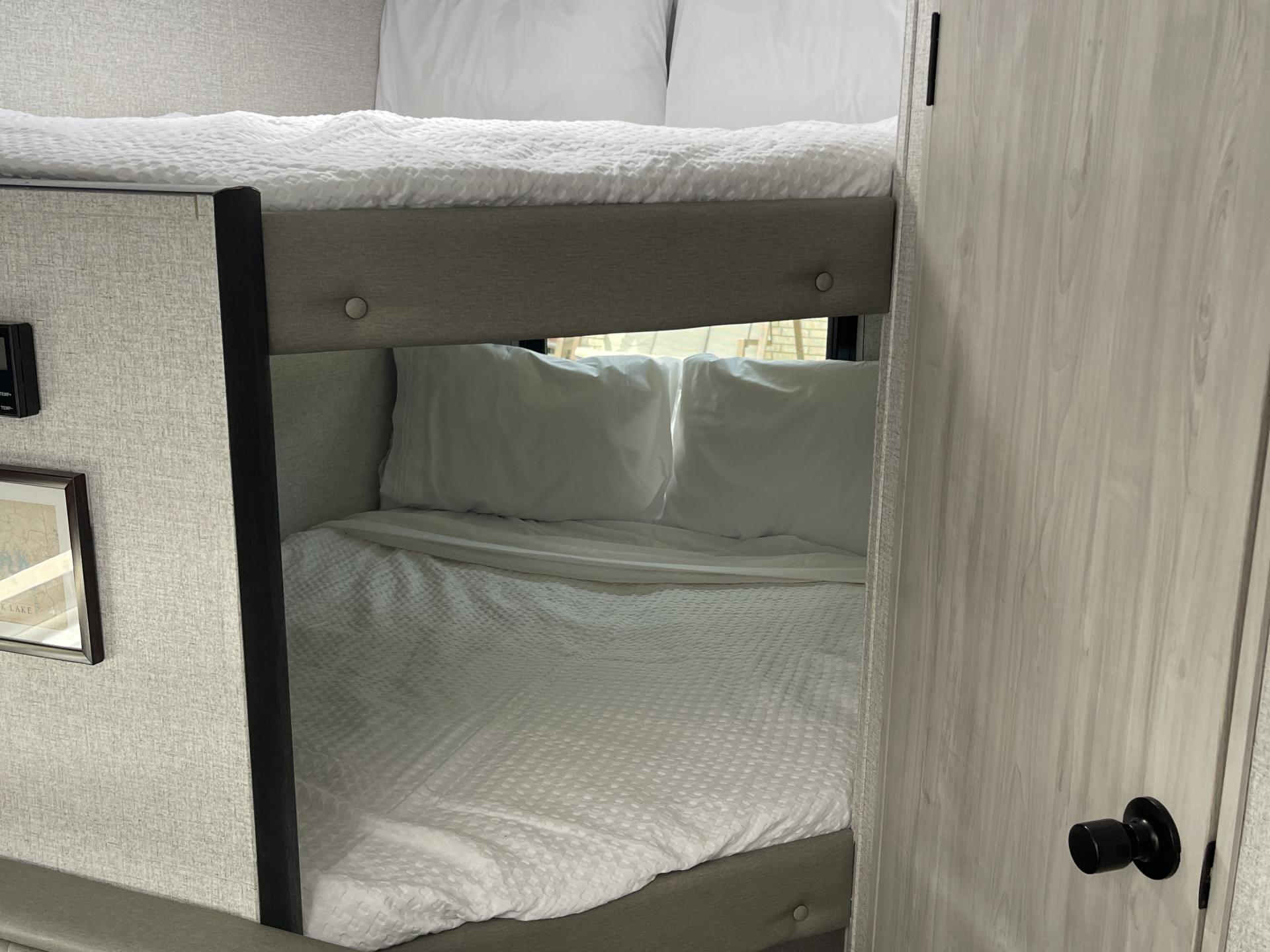 Cozy bunk beds with fresh white bedding in an RV rental interior, ideal for family travel or group adventures.. East to West Silver Lake 2023