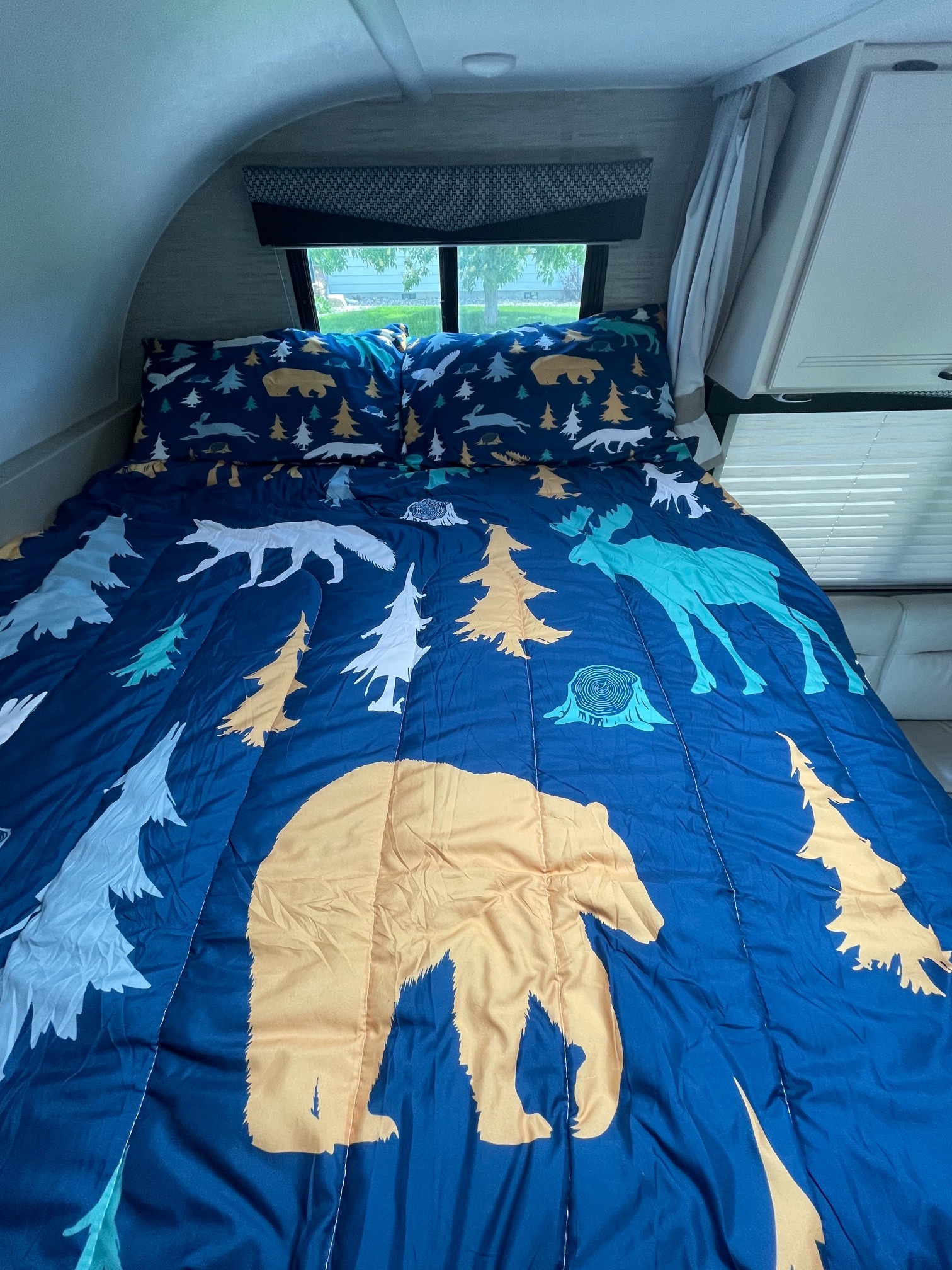 Cozy RV rental bed with nature-themed bedding featuring bears, moose, and foxes, ready for adventure.. Thor Freedom Elite 2022