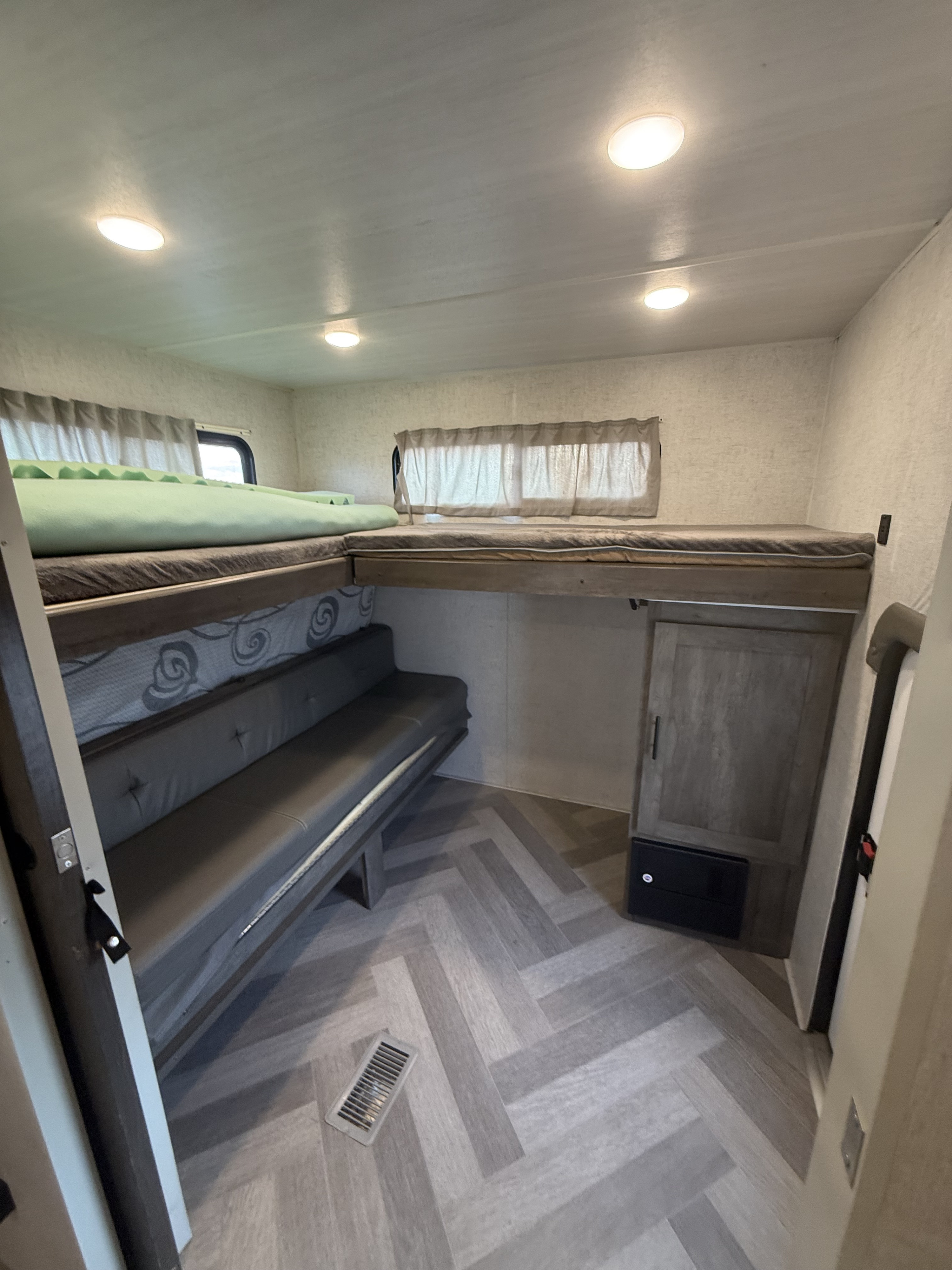 RV rental with stacked bunk beds over a sofa, bright lighting, and a modern herringbone floor. Ideal camper interior.. Forest River Salem 2021