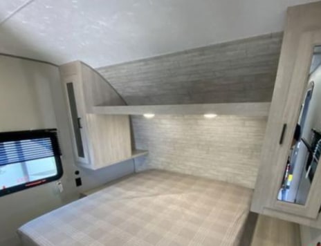 Explore this modern RV rental bedroom featuring a comfortable bed, window, and smart storage solutions for your journey.. Forest River Aurora Aurora 2026