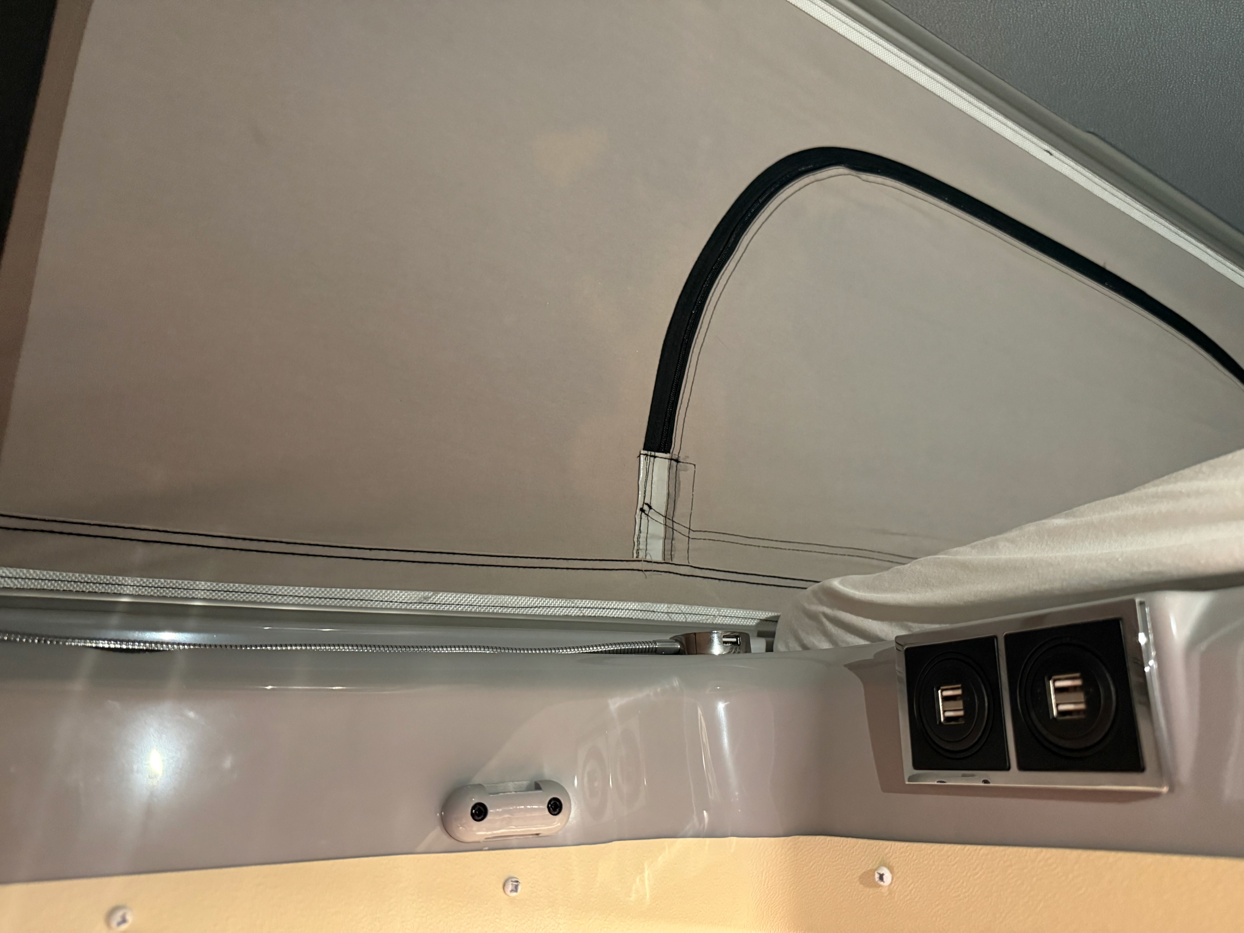 RV rental interior: pop-top fabric, dual USB ports, and a coiled hose (likely for light or shower) provide camper comfort.. Thor Scope 2023