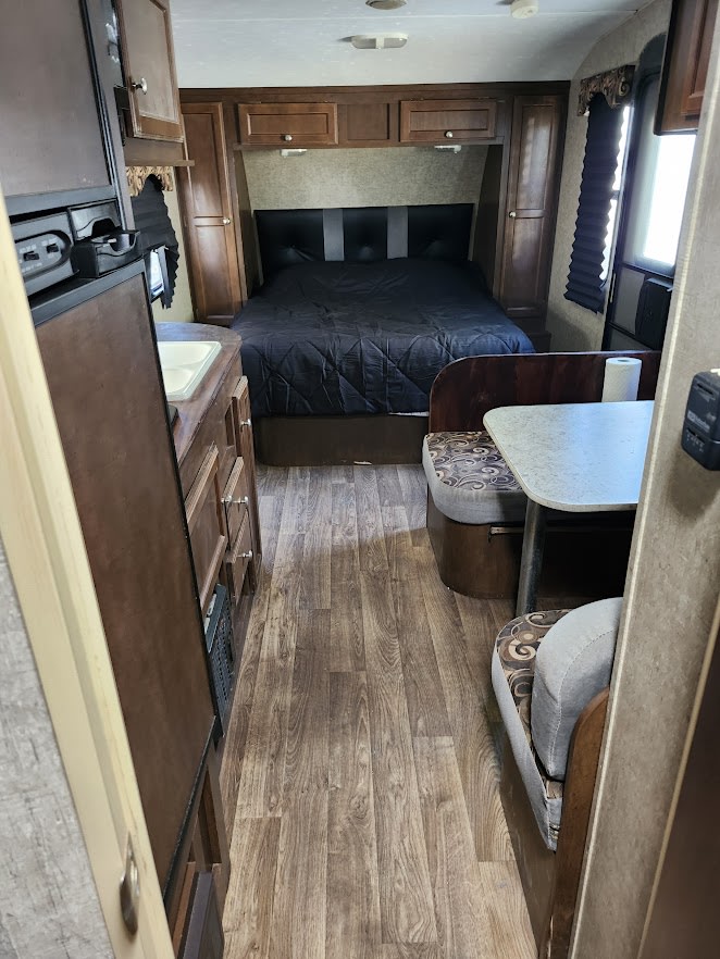 RV rental interior: A cozy bedroom with a large bed, a compact kitchen counter with a sink, and a comfortable dinette booth.. Sonic Sonic Trailer 2019