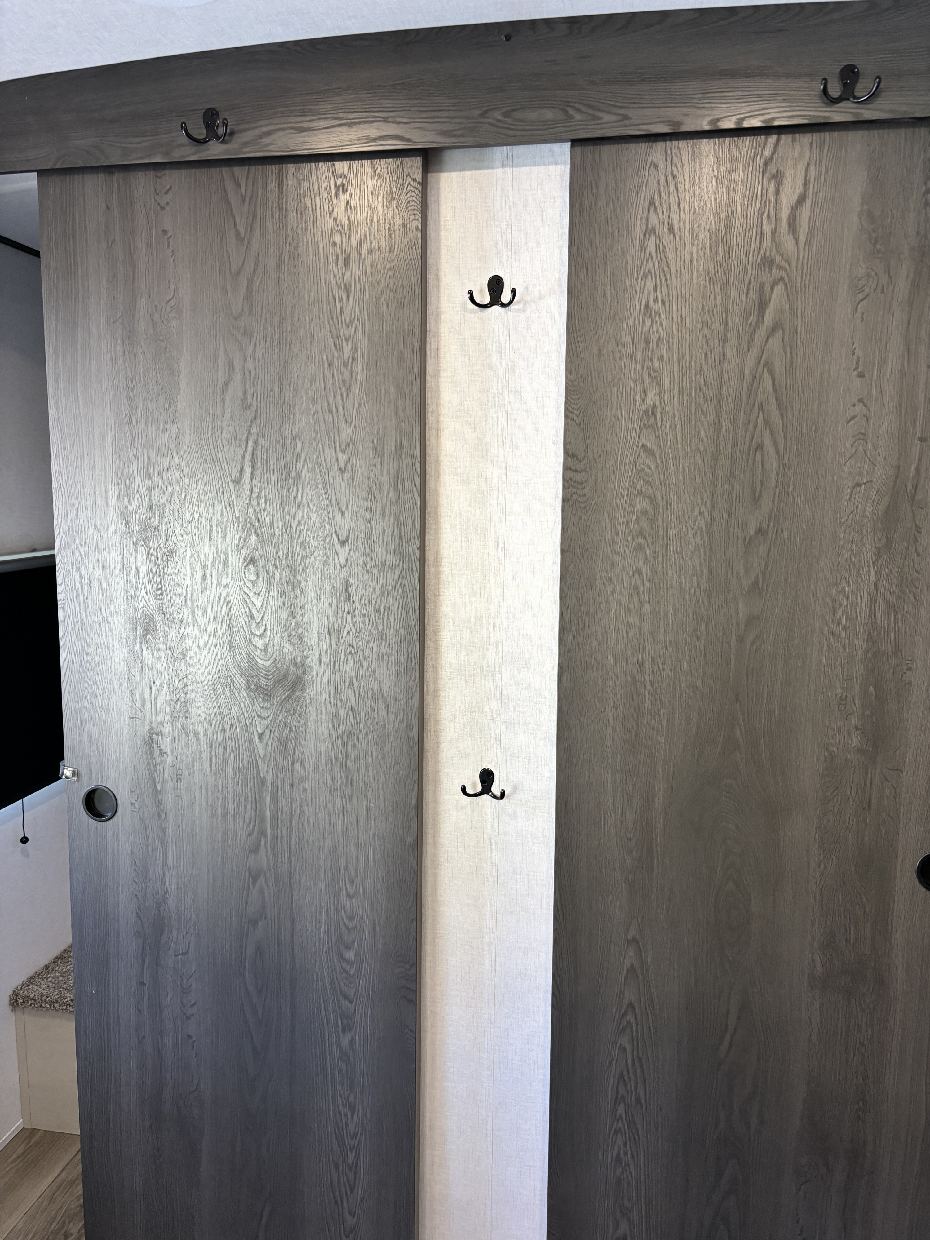 RV rental: Sleek closet features dark wood-grain sliding doors, a central fabric panel with hooks, and top coat hooks.. Forest River Coachmen Northern Spirit Ultra Lite 2026