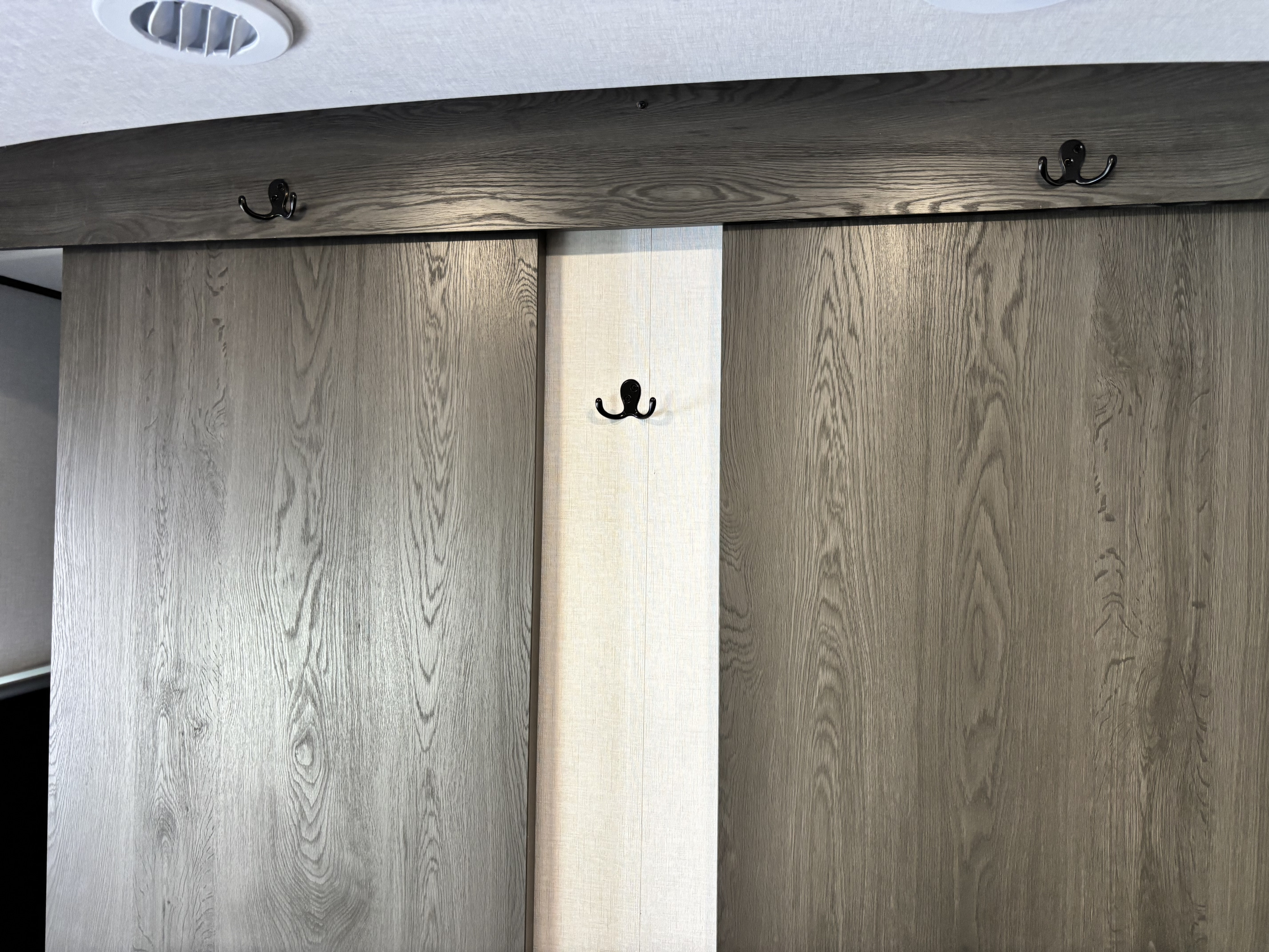 RV rental interior features: wood-look sliding doors, wall hooks for storage, and an overhead ceiling vent.. Forest River Coachmen Northern Spirit Ultra Lite 2026