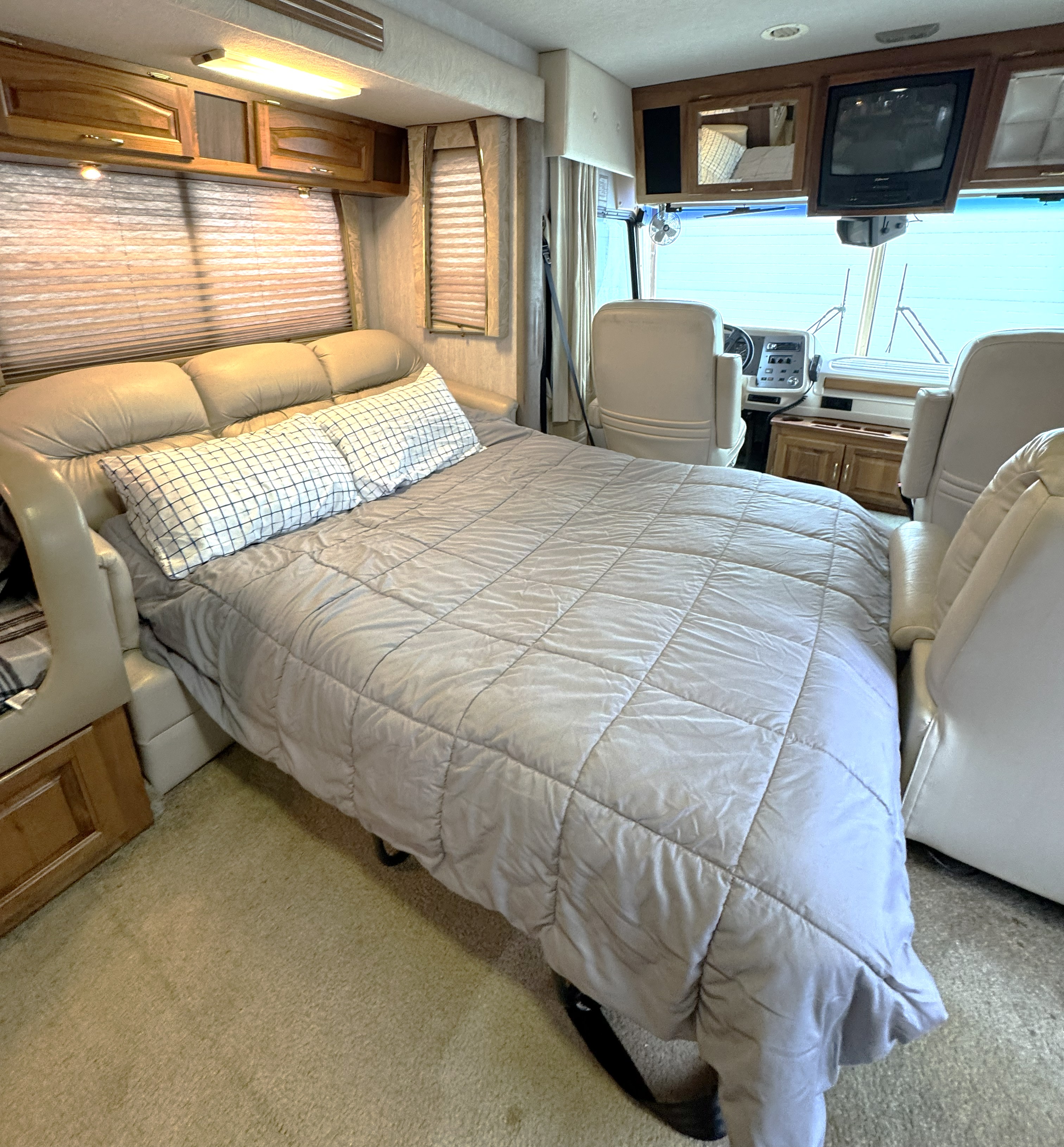 Inside this RV rental, a comfy sofa-bed, wood cabinets, and driver's area are visible, ready for travel.. National Tradewinds 1998