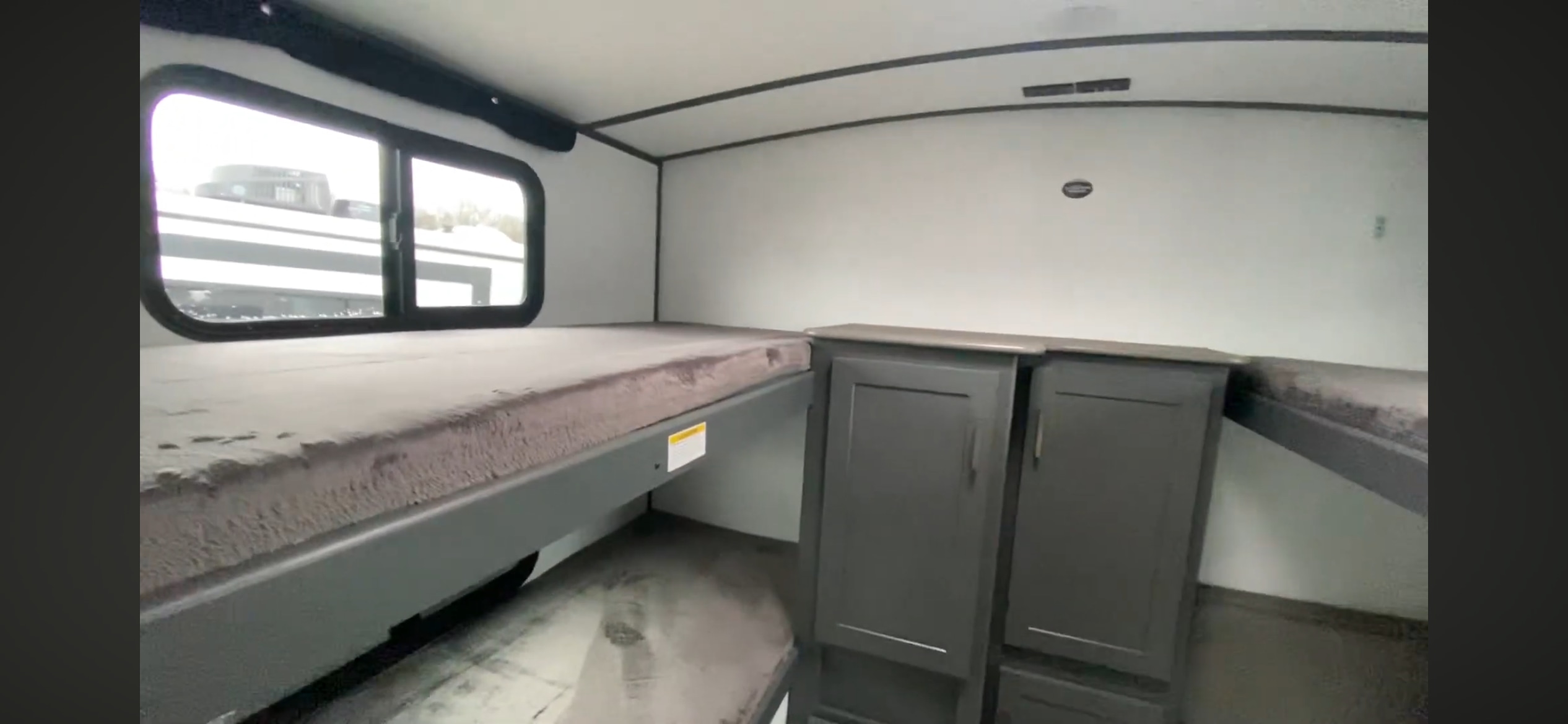 RV rental interior: bunk beds with cozy gray mattresses and dark storage cabinets. Ideal for a family getaway.. Keystone RV Bullet Ultra Lite 2023