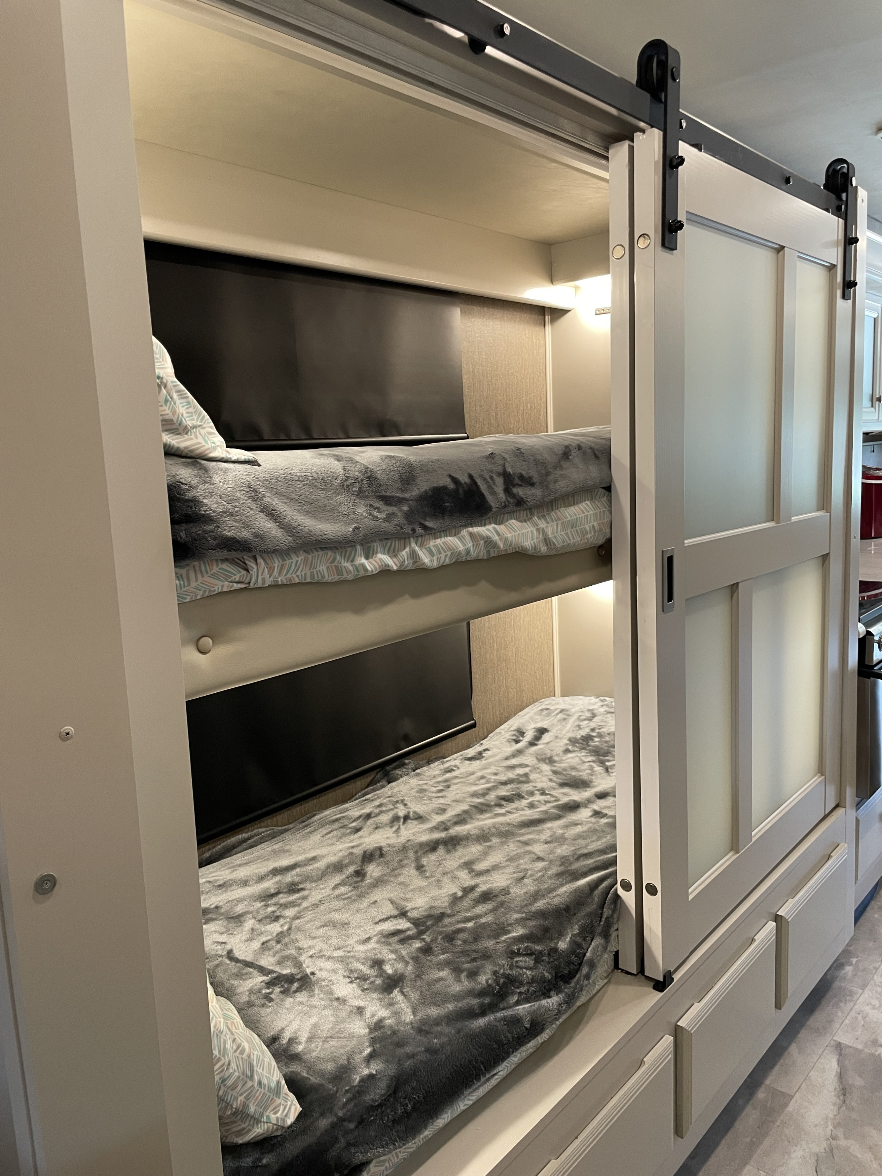 Cozy RV rental bunk beds with a sliding barn door, providing a comfortable sleeping area for family adventures.. Holiday Rambler Admiral 2021
