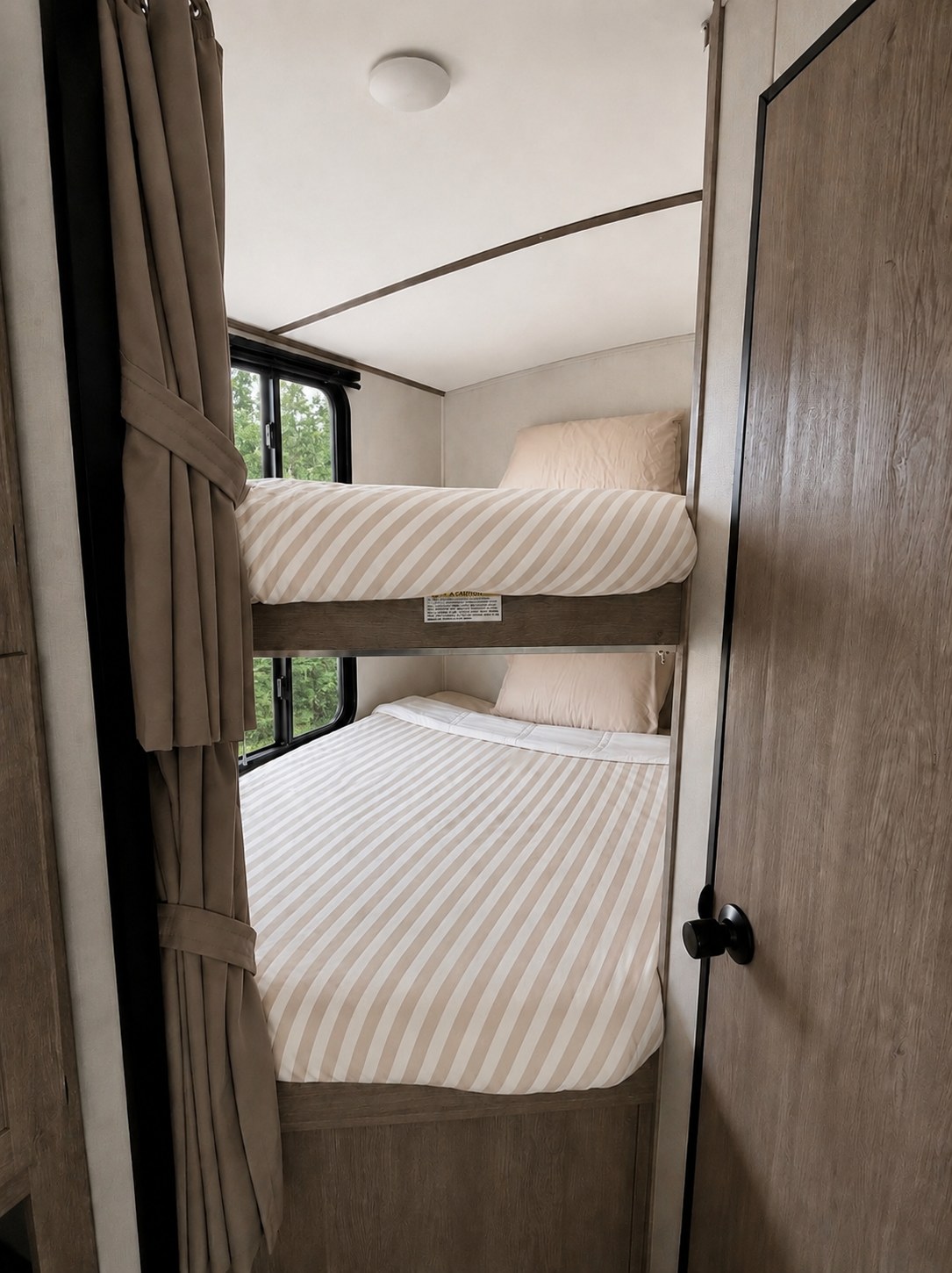 Cozy bunk beds in this RV rental, complete with striped bedding and windows. A comfortable sleeping area for your adventure.. Keystone RV Springdale 2021