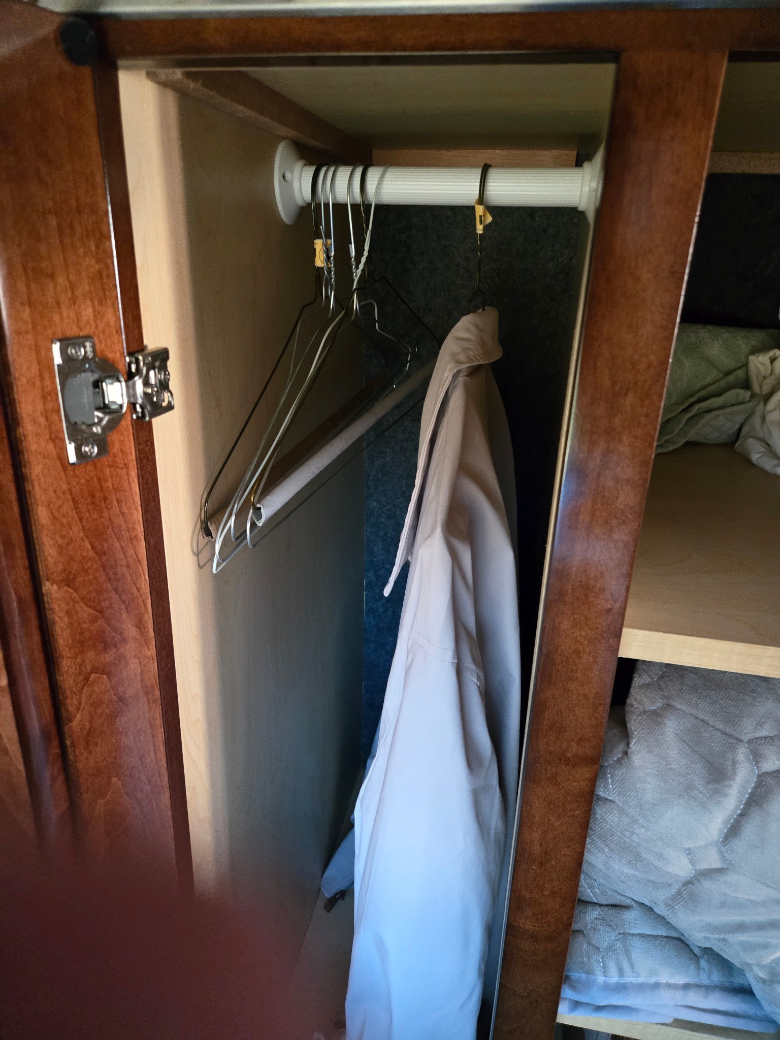 RV rental closet: view inside a small wardrobe with a tension rod, hangers, a jacket, and shelved storage for bedding. Compact & functional.. Coachmen Galleria 2023