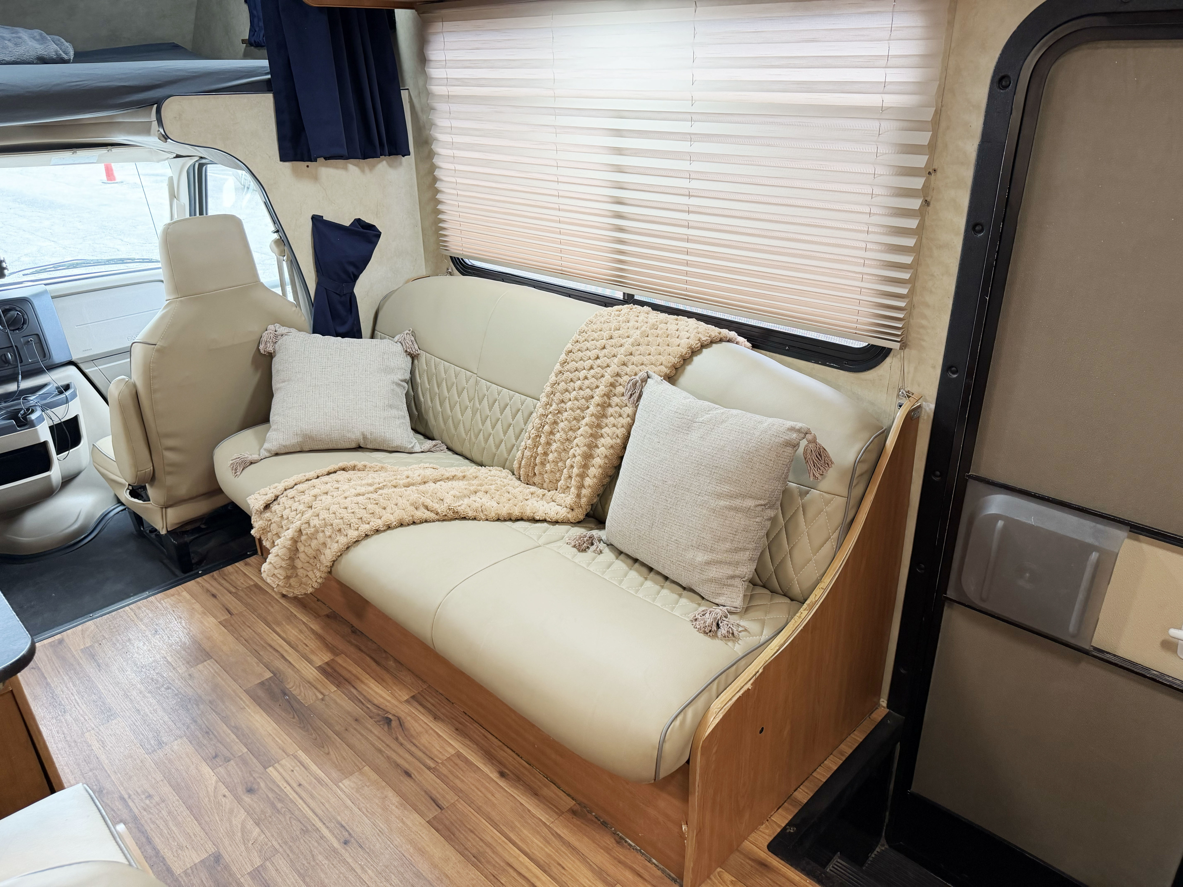 Inviting RV rental interior showcasing a comfortable sofa with pillows & blanket, wood floor, and overhead bed.. Thor Majestic 2014