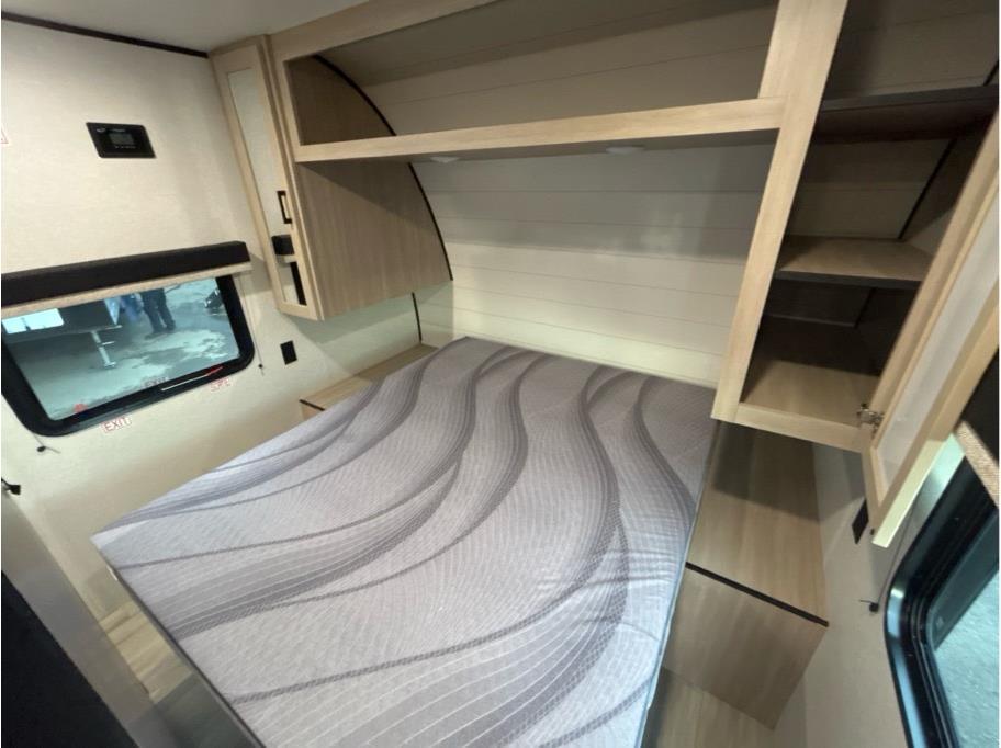 Inside an RV rental, a cozy bedroom with a wave-patterned mattress, ample overhead storage, and a window.. Heartland Powler 2026