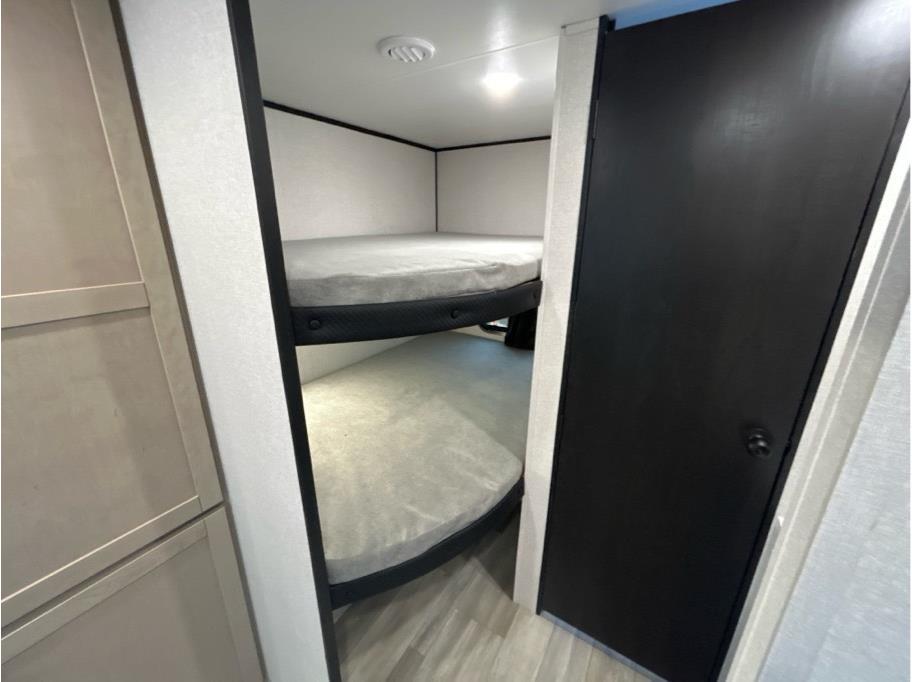RV rental interior: A compact sleeping area with two stacked bunk beds, light mattresses, and dark frames, next to a black door.. Heartland Powler 2026