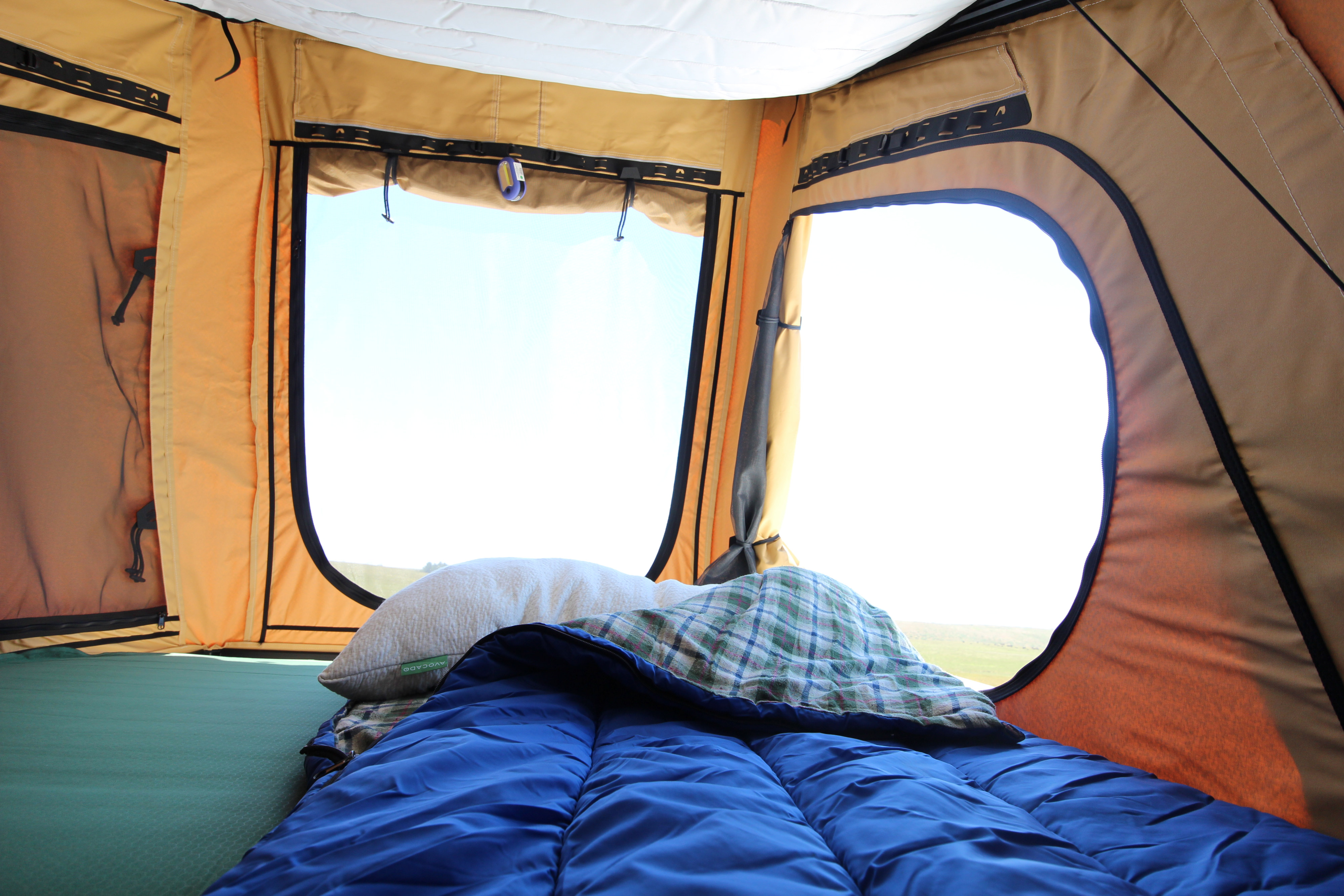 Cozy RV rental tent interior: green sleeping pad, blue sleeping bag, pillow, and a bright outdoor view through two windows.. Ford Ford F150 2017