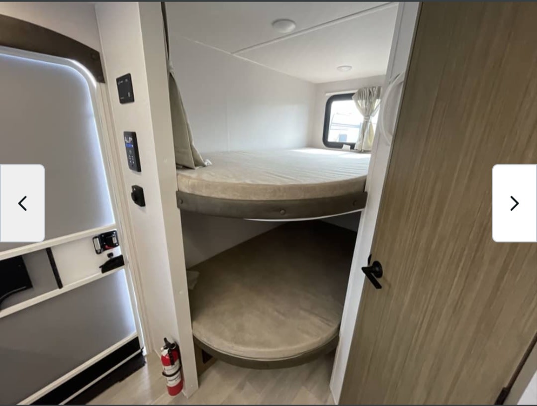Inside this RV rental, find bunk beds in a cozy sleeping area. A window, control panels, and fire extinguisher are visible.. Forest River Salem 2026