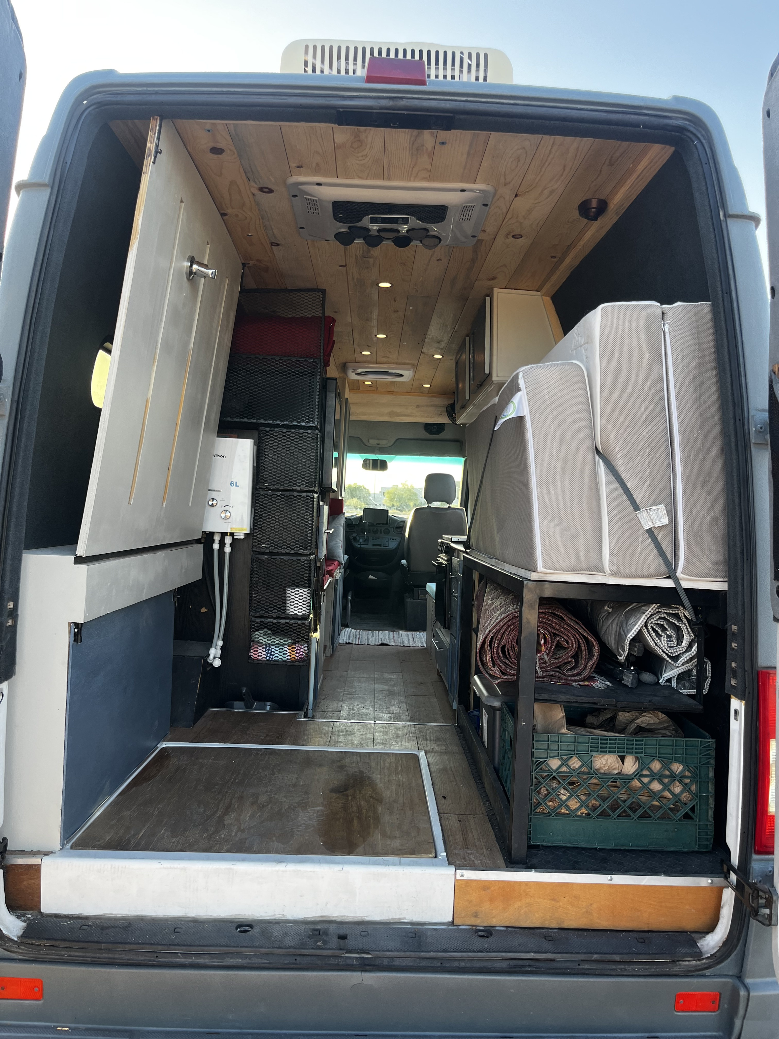 Inside an RV rental van, featuring a custom shower, wooden ceiling, bed, and storage. Ready for adventure.. Mercedes Sprinter 2500 2002