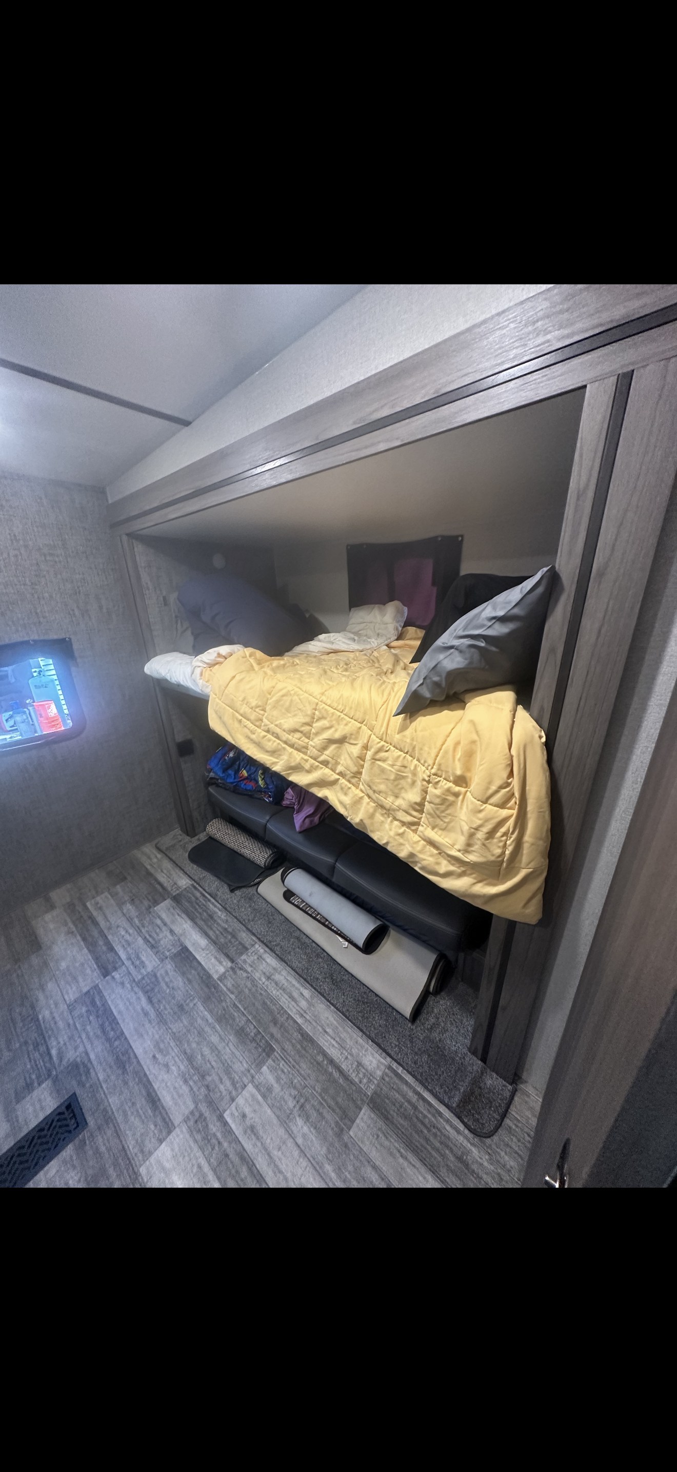 Cozy RV rental interior: bunk bed with yellow comforter, sofa below, wood-look floor, and small TV.. Cross Roads RV 4Ydfvlr25n6360061 2022