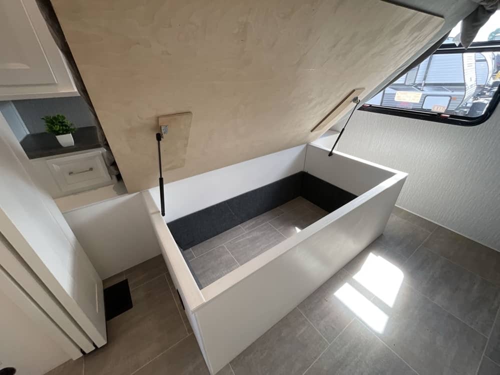 RV rental: Lifted bed platform reveals spacious under-bed storage with gas struts, clean interior, and tiled floor.. Forest River Coachmen Mirada 2023