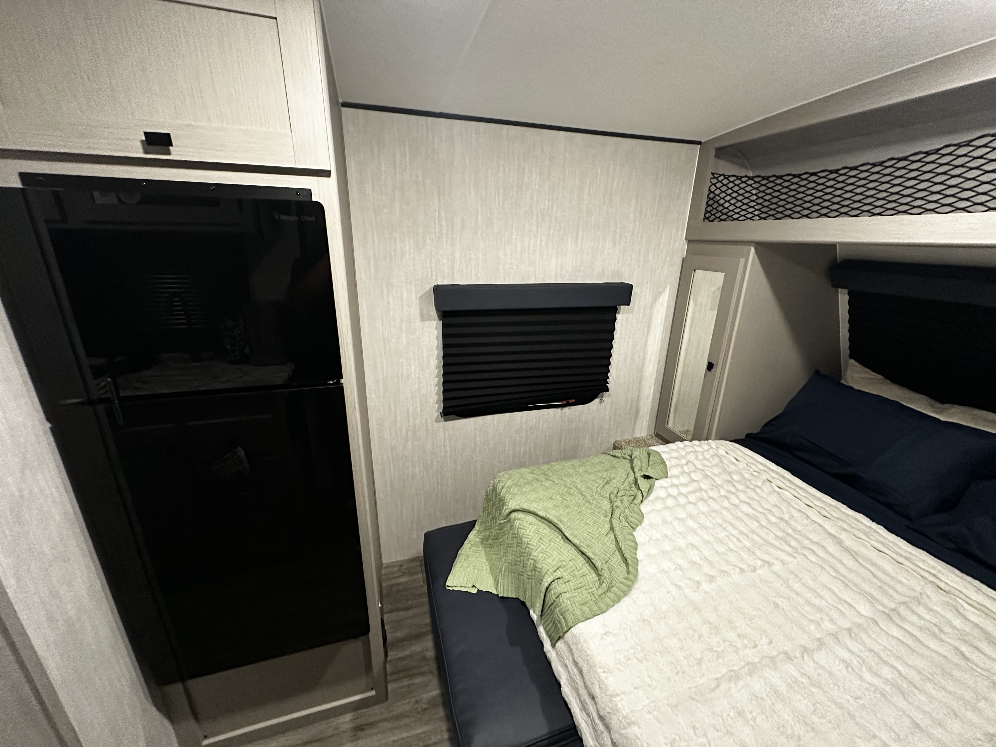 RV rental bedroom: a cozy interior featuring a bed, refrigerator, mirrored wardrobe, and practical overhead storage.. Coachmen RMT18R 2024