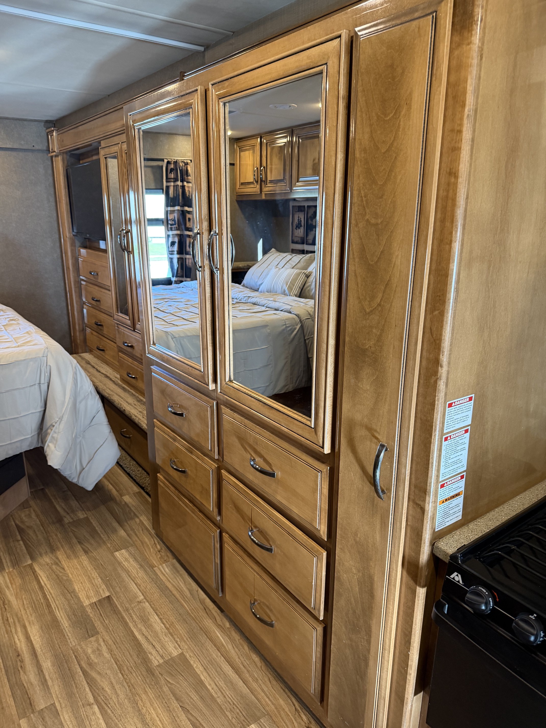 RV rental interior showing a bedroom with a mirrored wardrobe, dresser drawers, and wood-look flooring.. Thor Quantum 2017