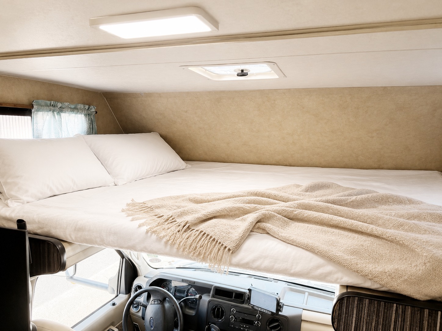 This RV rental's over-cab sleeping bunk features a bright bed with white sheets, pillows, and a cozy throw blanket.. Thor Majestic 2014