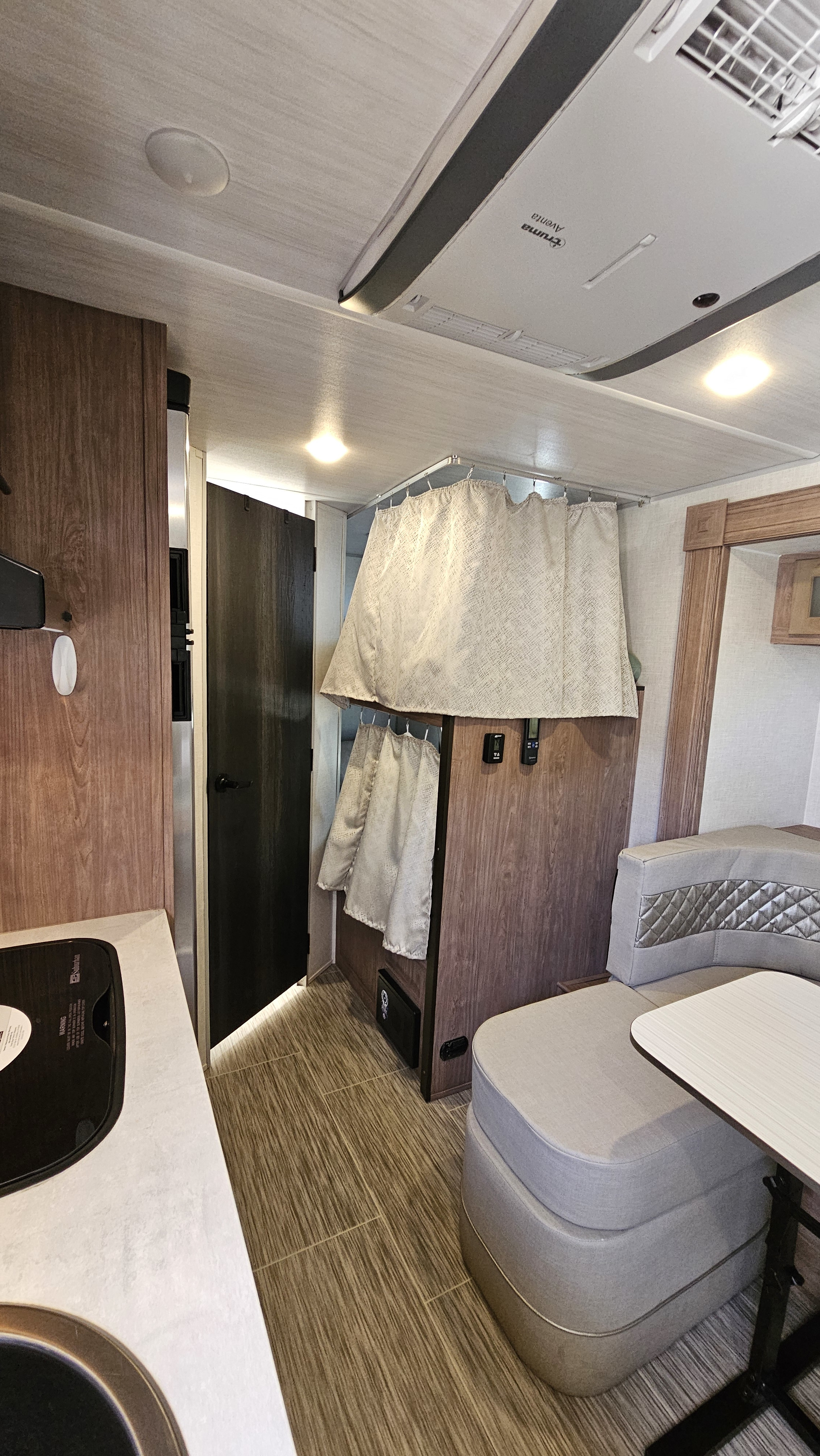RV rental interior featuring a kitchen, bunk beds with curtains, and a dinette. A compact and functional space.. No Boundaries 19 2022