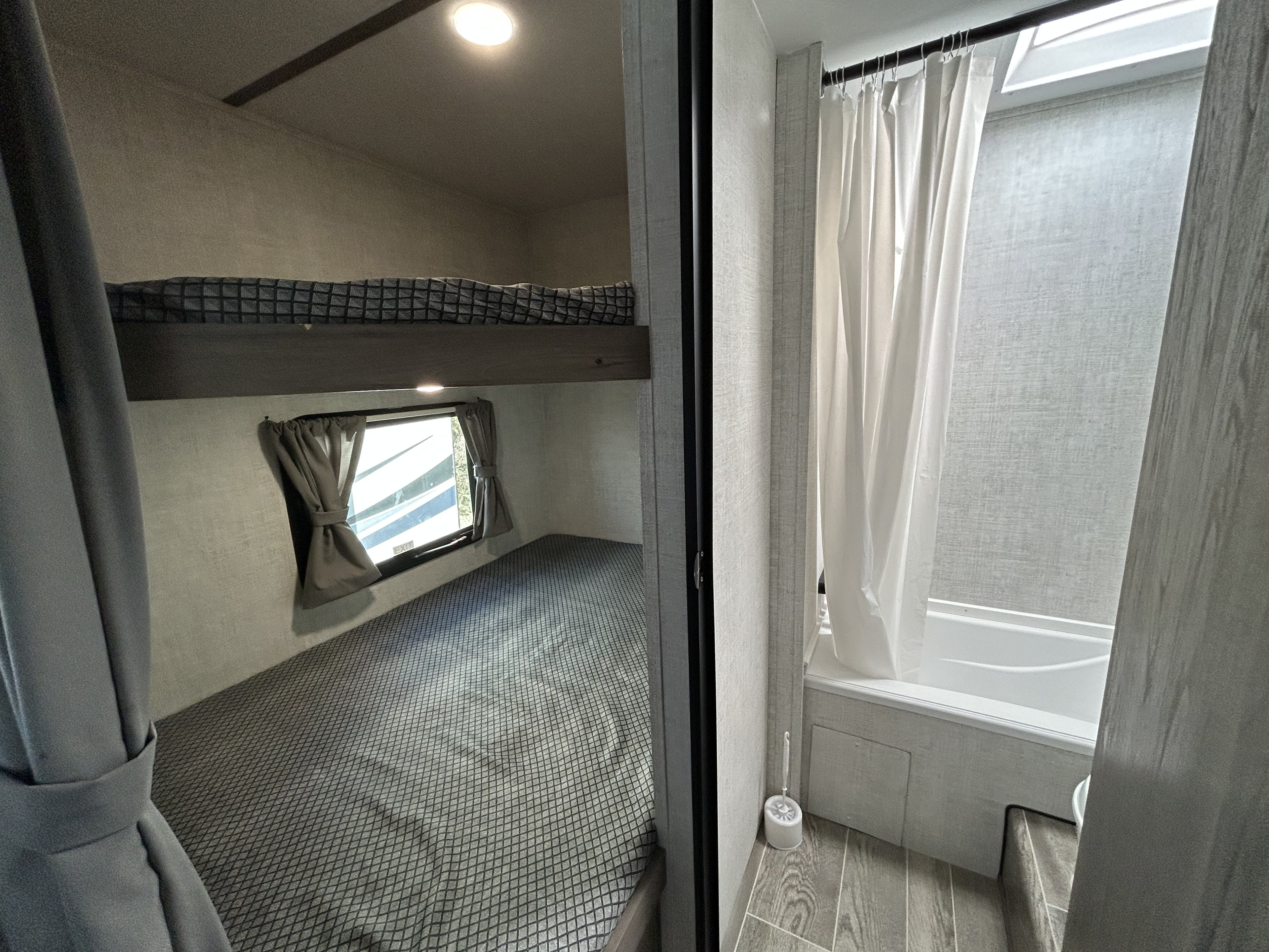 RV rental interior: cozy bunk beds with a window and a compact bathroom featuring a shower/tub, ideal for family trips.. Gulf Stream Highwood River 2022
