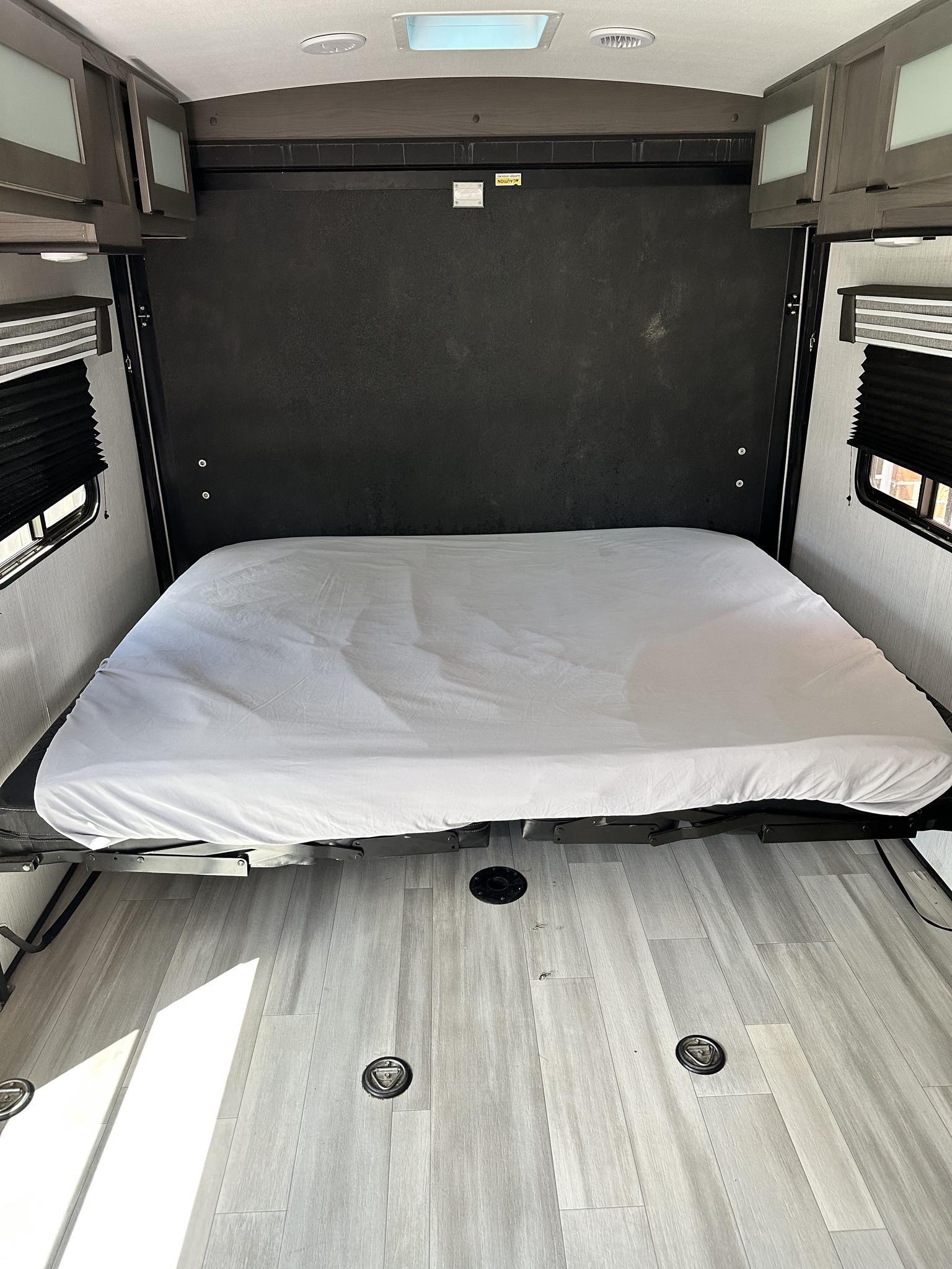 RV rental: Interior view of a fold-down bed with white sheet, overhead cabinets, window blinds, and light wood-look floor.. Cruiser Rv Corp MPG 2023