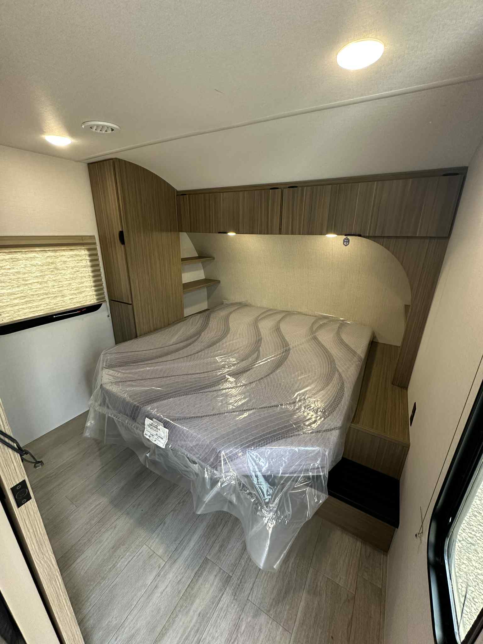 Bright RV rental bedroom: cozy bed with plastic cover, modern cabinetry, shelving, and window with blinds.. Forest River Salem FSX 266BHLE 2026