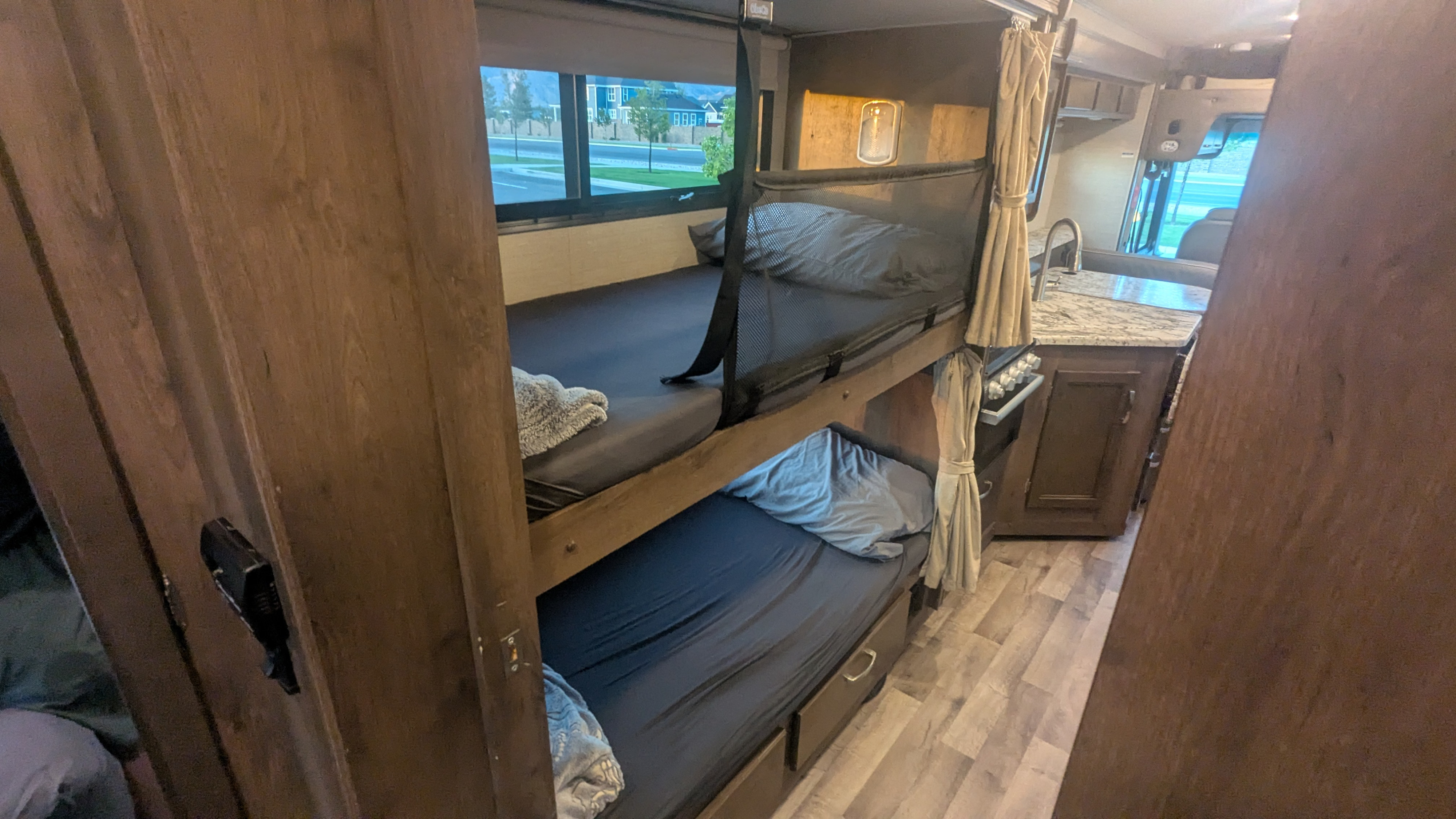 RV rental interior features bunk beds with safety net, visible kitchen, and outdoor view from window.. Jayco Alante 2020