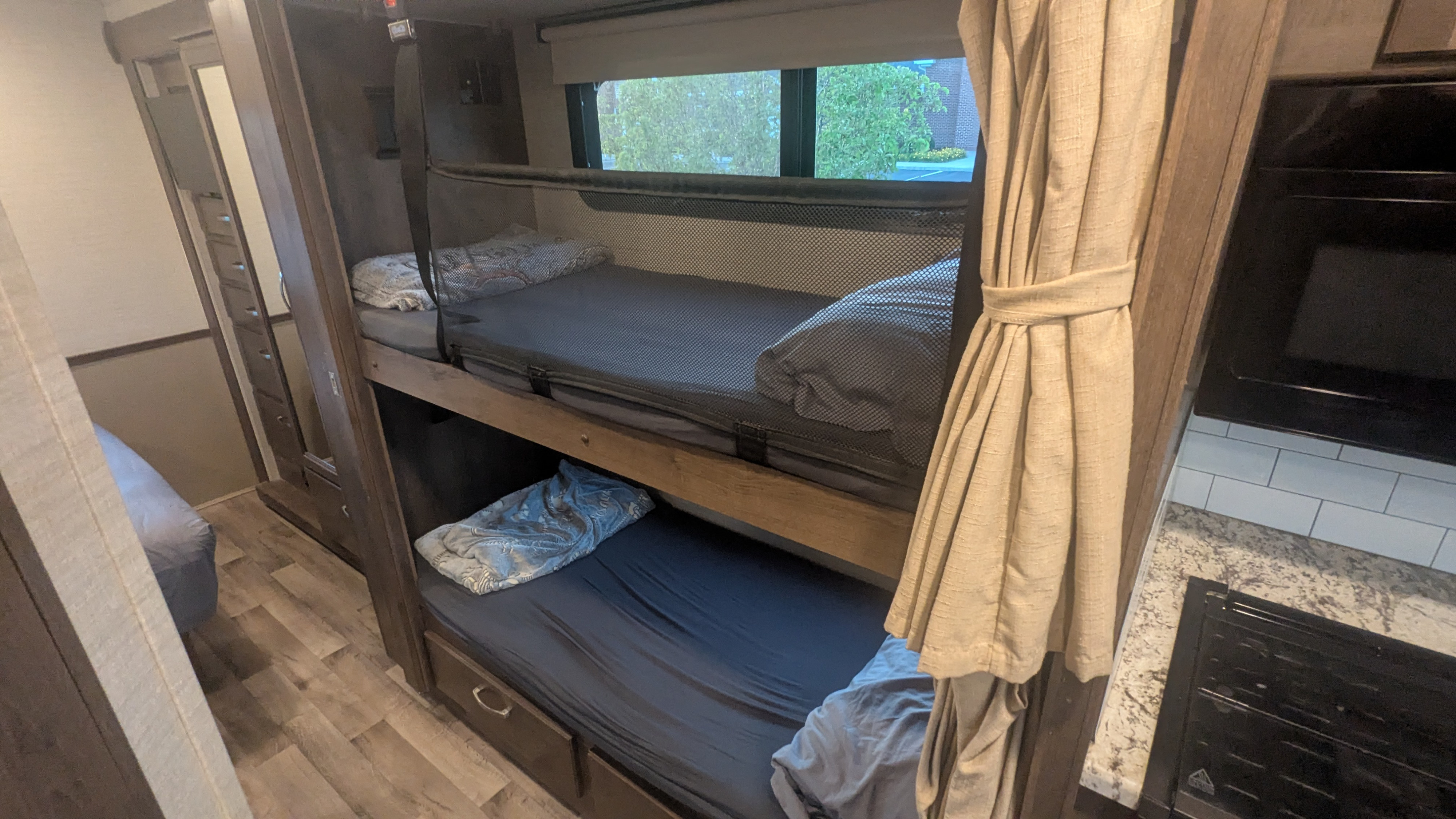 This RV rental offers practical bunk beds with safety nets, a mirrored wardrobe, and a peek at the kitchen, perfect for travel.. Jayco Alante 2020