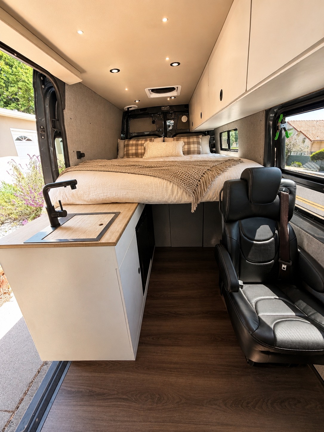 This modern RV rental interior features a raised bed, compact kitchenette, and passenger seat, ready for comfortable travel.. Mercedes-Benz Sprinter 2019