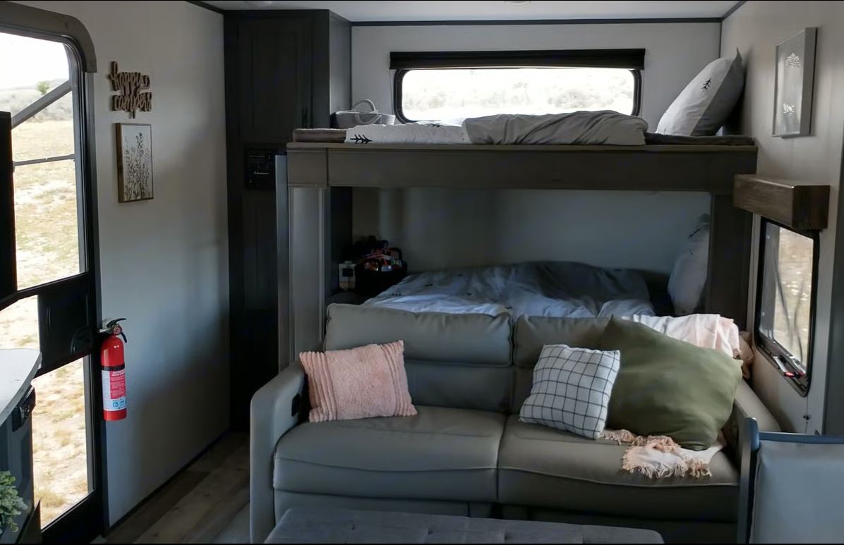 Cozy RV rental interior with bunk beds, sofa, and fire extinguisher for safety. Ideal for family travel and adventure.. Aspen Trail LE 2021