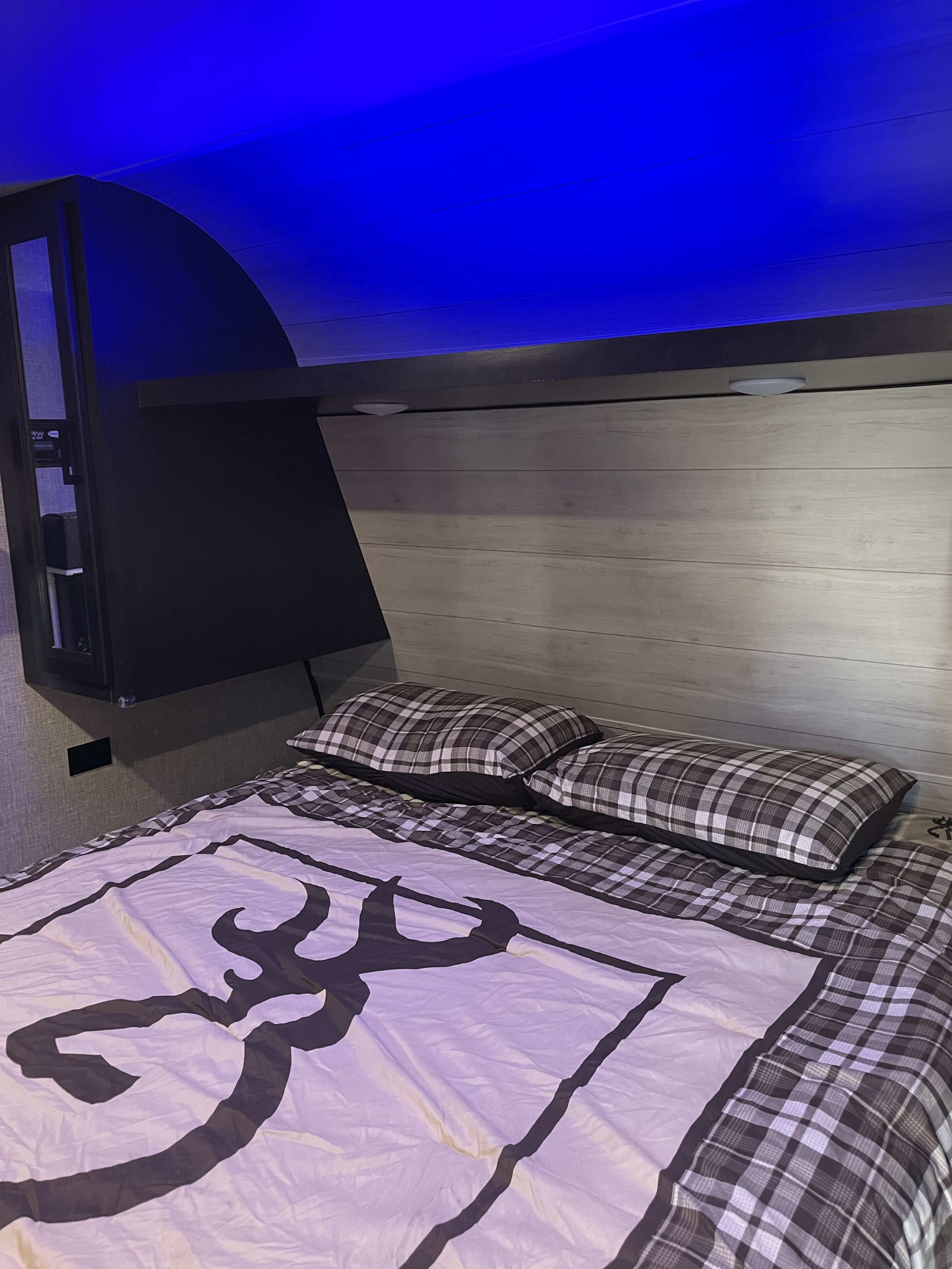Experience comfort in this rv rental bedroom with blue LED lighting, plaid bedding, and a unique deer head logo comforter.. Jayco Jay Flight SLX Rocky Mountain Edition 2021