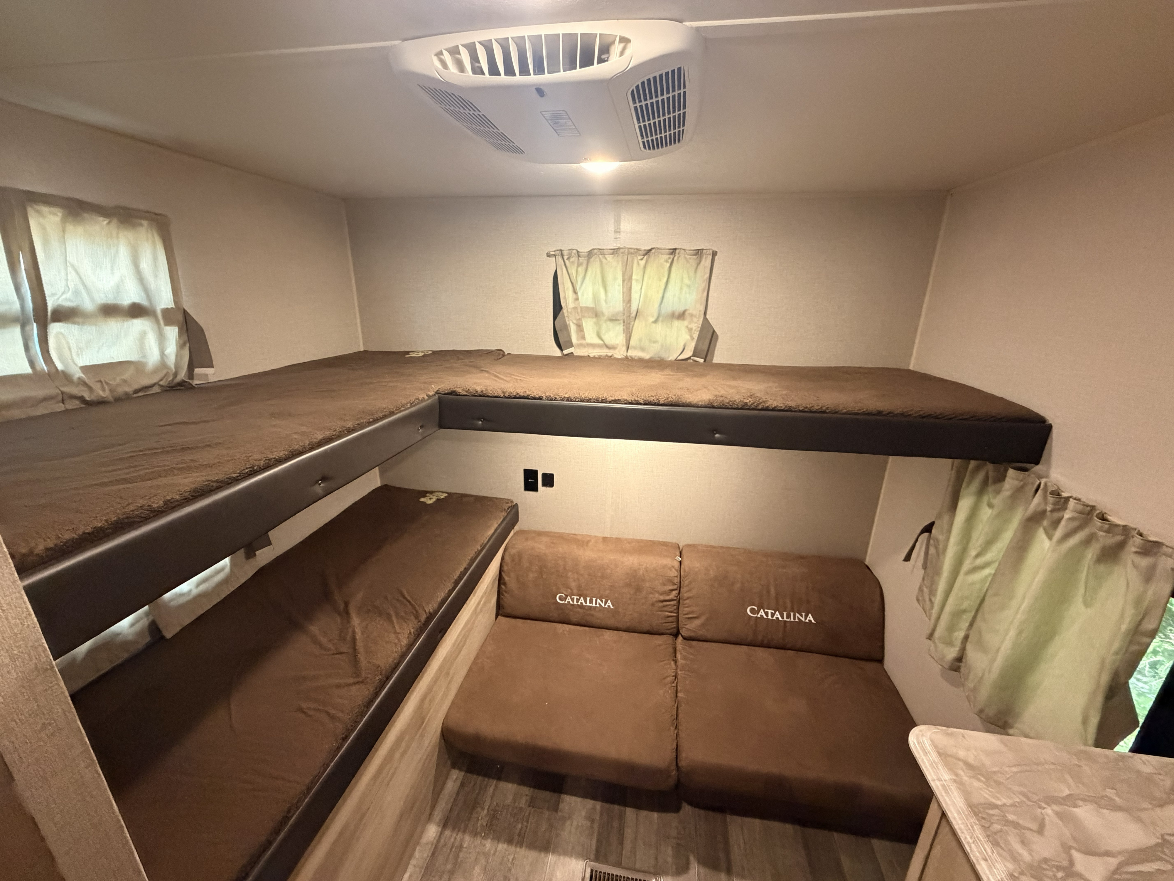 This rv rental offers cozy L-shaped bunk beds with brown cushions and a Catalina-branded seating area, perfect for family adventure.. Coachmen Other 2021
