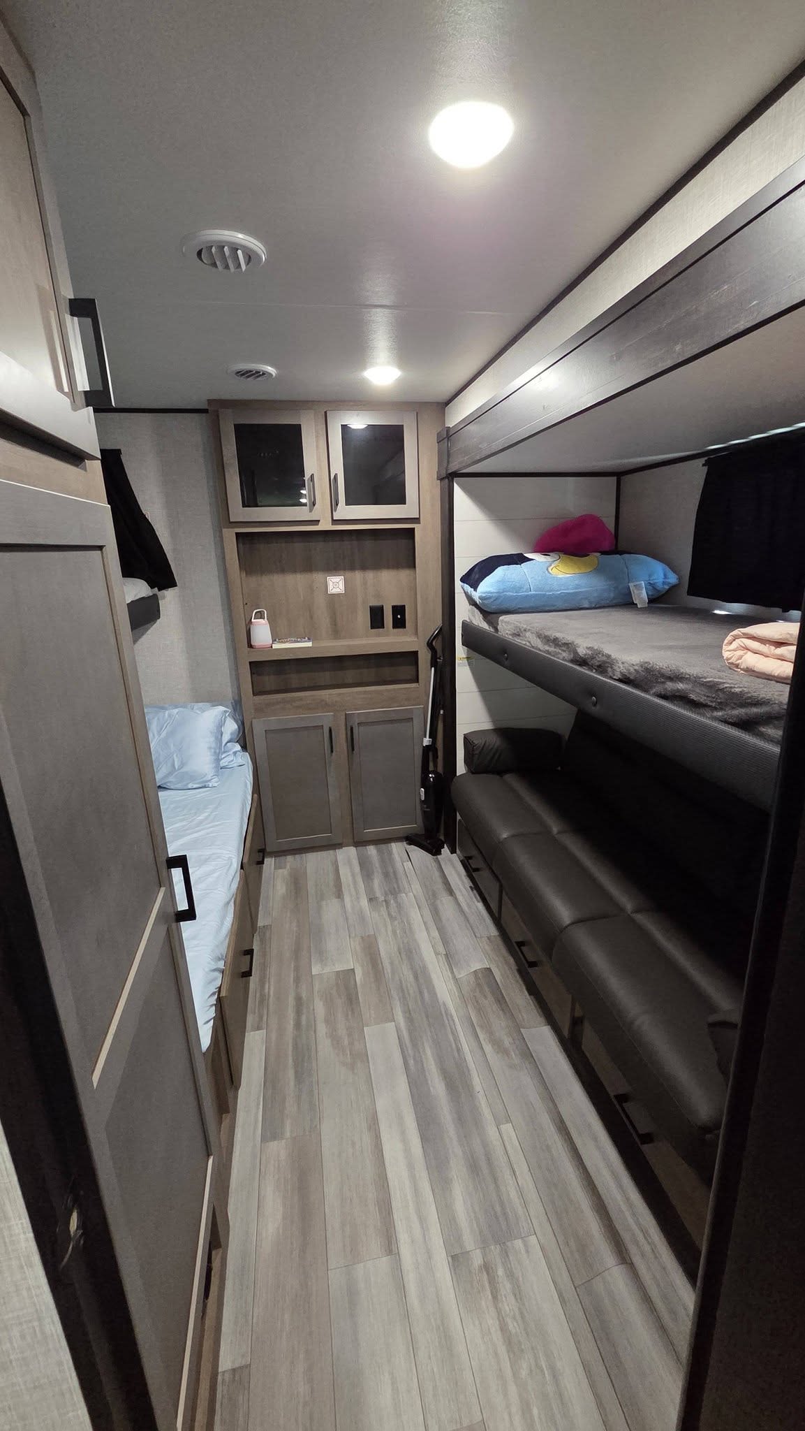 Modern RV rental bunkhouse: view of multiple beds, a sofa, and storage cabinets, with light wood-look flooring.. Jayco Jay Flight 2024