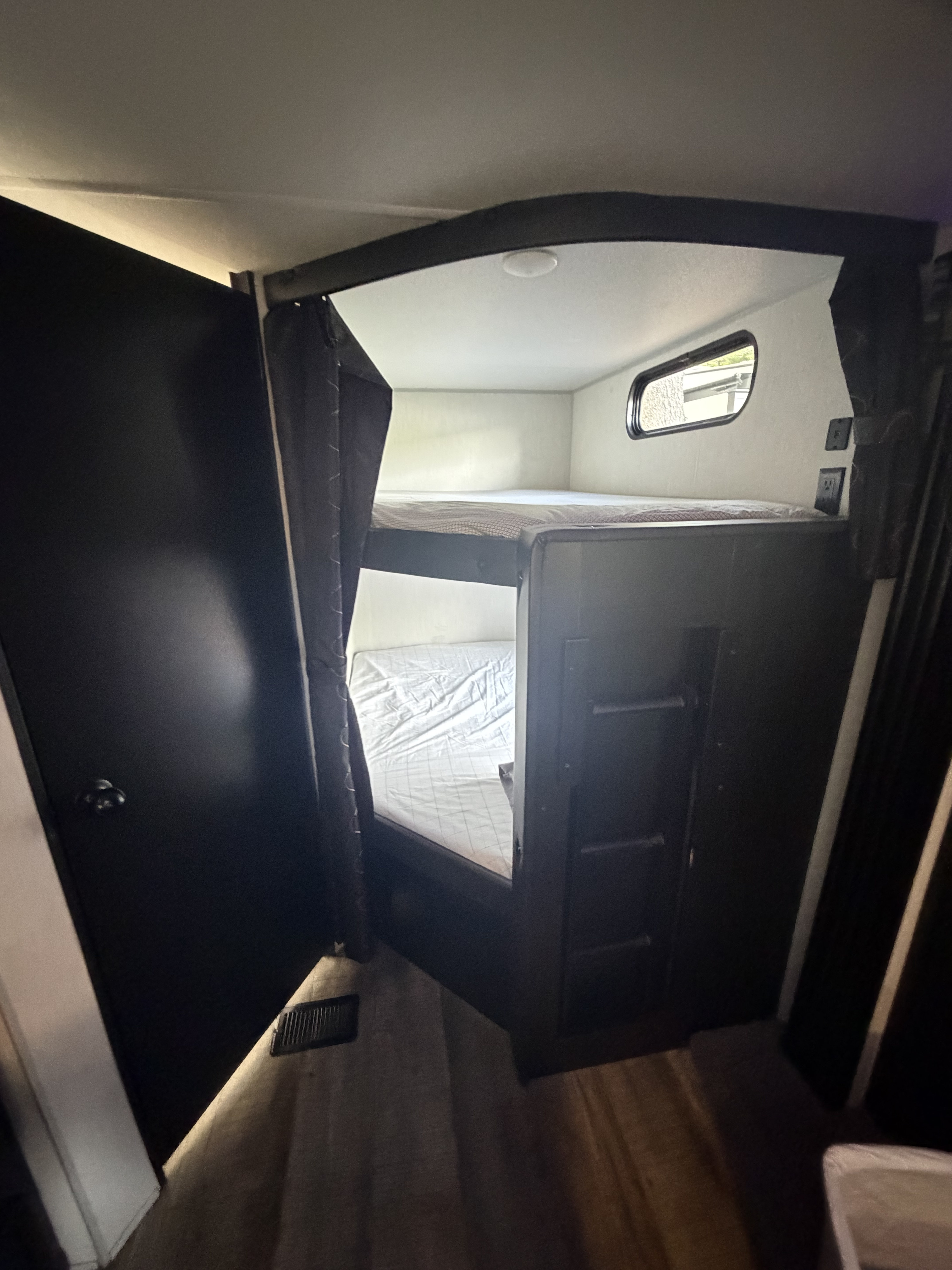 Cozy bunk beds in an RV rental, complete with privacy curtains, a window for light, and a built-in ladder for access.. Forest River Cherokee 2023