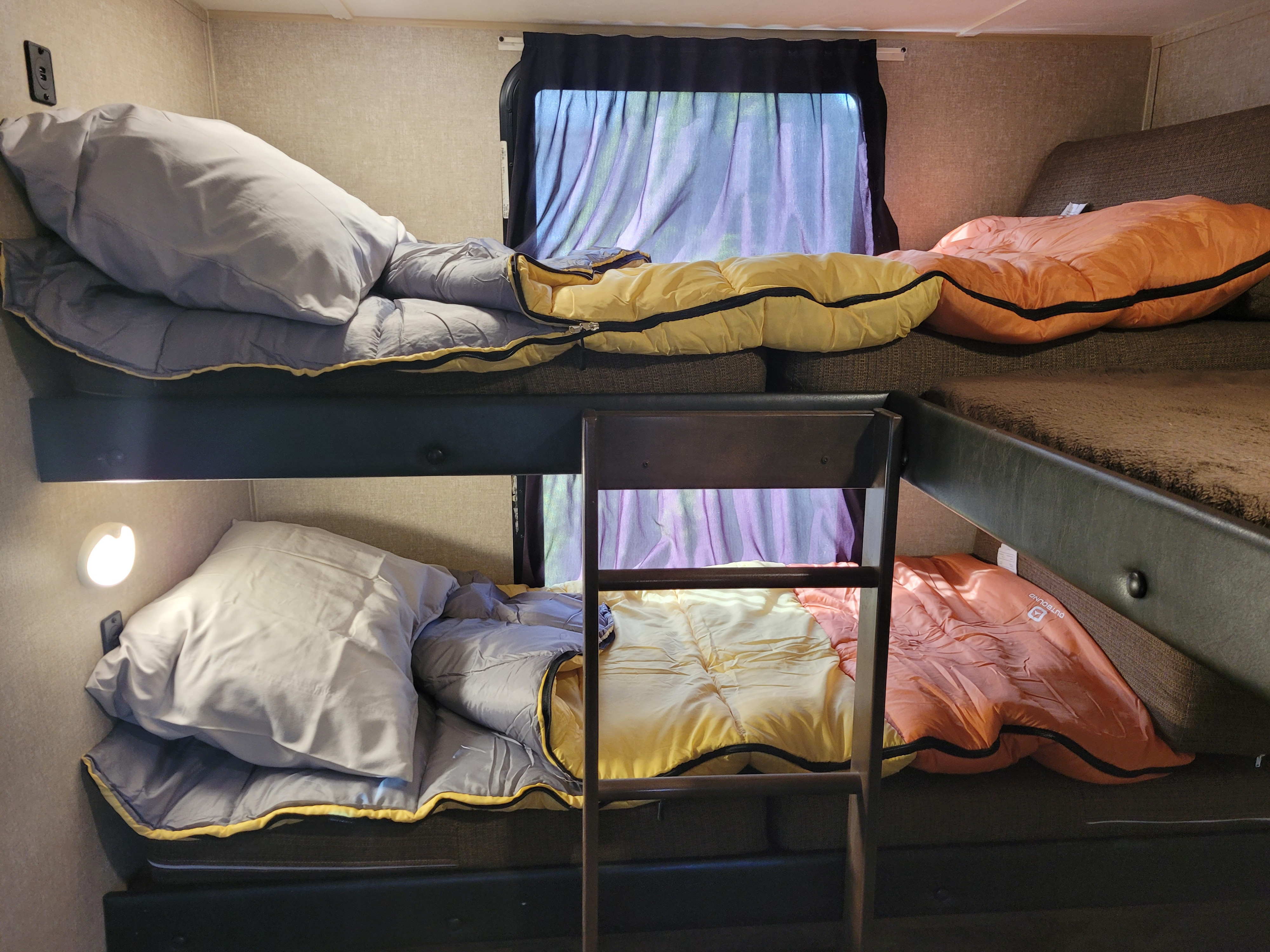 RV rental bunk beds: Four cozy sleeping spots with colorful sleeping bags and pillows, ideal for family travel.. Forest River Vibe Extreme Lite 2017