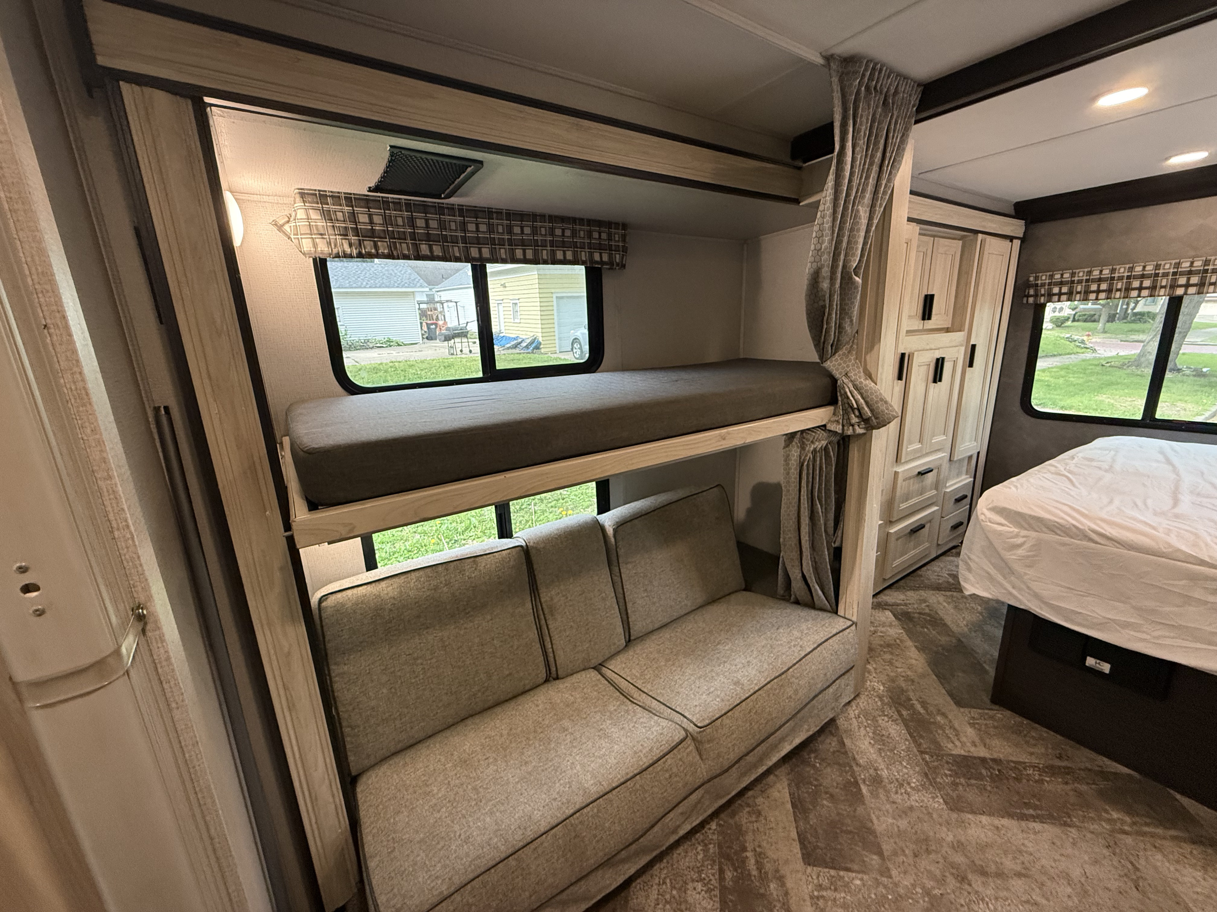 RV rental interior features bunk beds with a sofa below, a main bed, and ample storage, providing flexible family living.. Forest River Sunseeker LE 2021