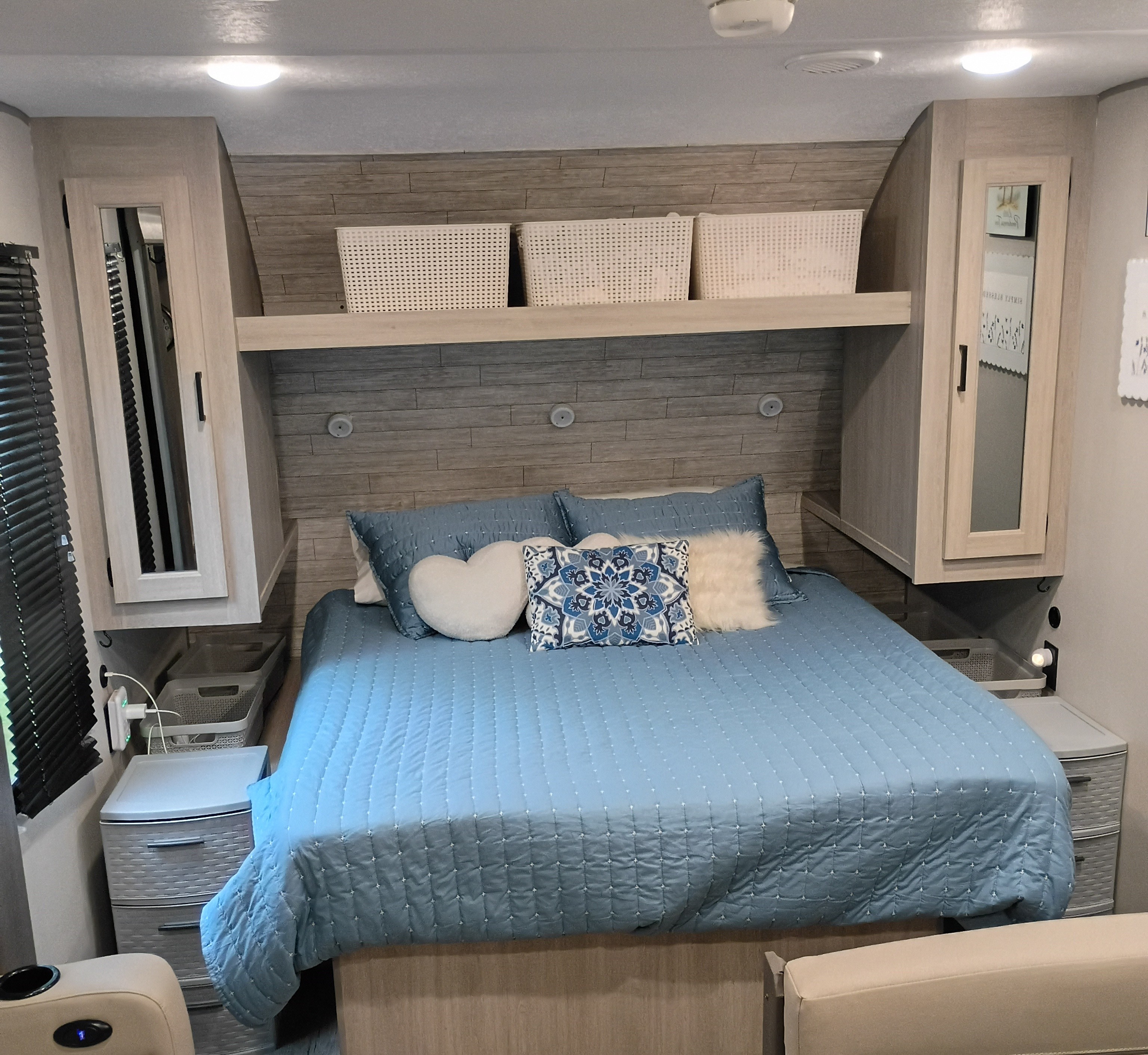 Inviting RV rental bedroom with a blue quilted bed, decorative pillows, overhead storage, and nightstands.. Coachmen Other 2025