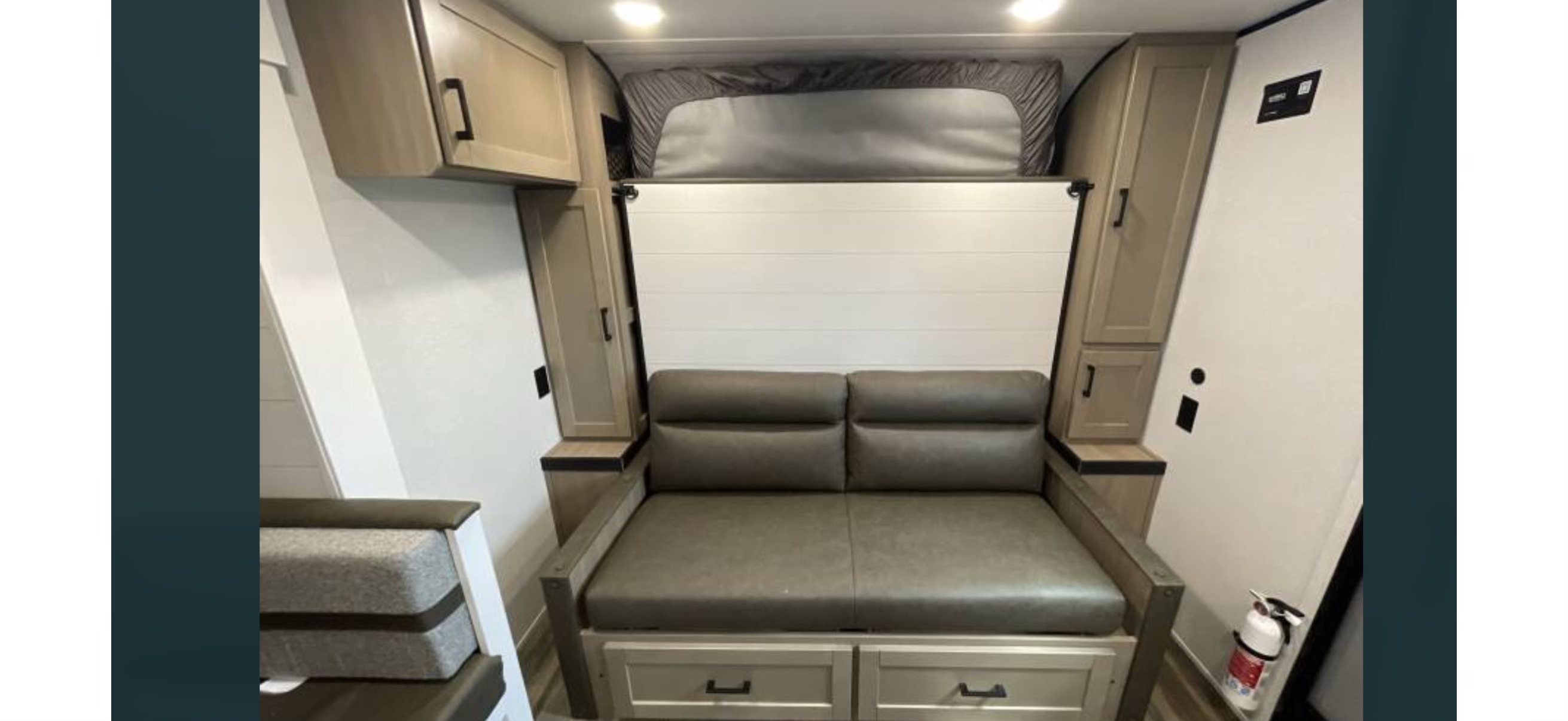 RV rental: Compact interior with a gray jackknife sofa, an upper bunk bed, and wood-toned storage cabinets.. Highland Ridge RV Colt 2026
