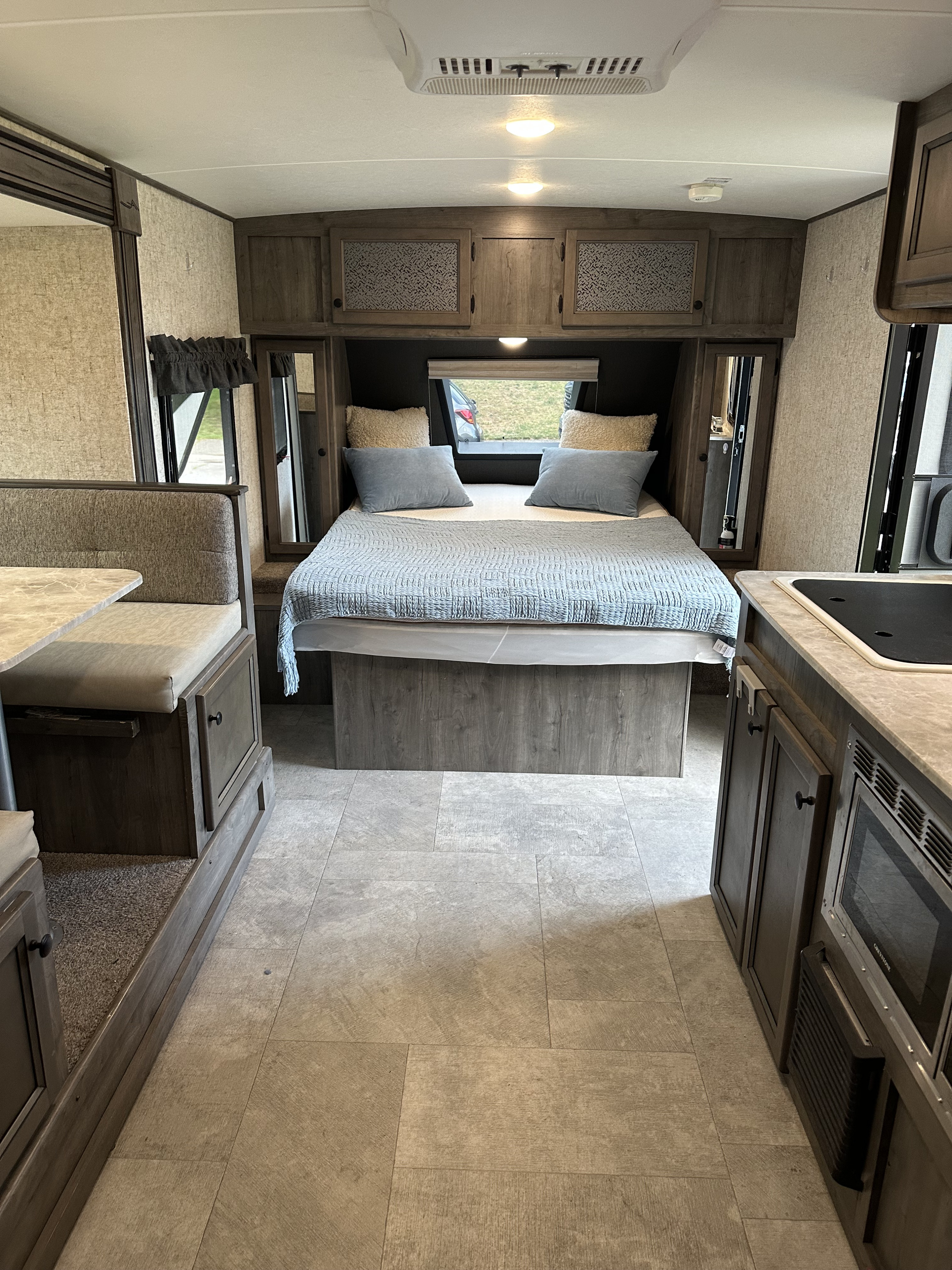 Modern RV rental interior, featuring a comfortable bedroom with blue bedding, dinette, and kitchenette. Ideal for your next trip.. Coachmen Apex Nano 2020
