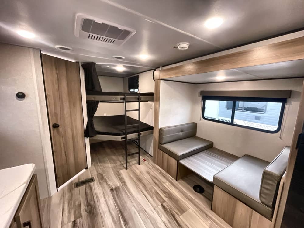 Spacious rv rental interior featuring bunk beds, a dinette, and wood-look flooring, perfect for family adventures.. Keystone RV COLEMAN LITE 2026