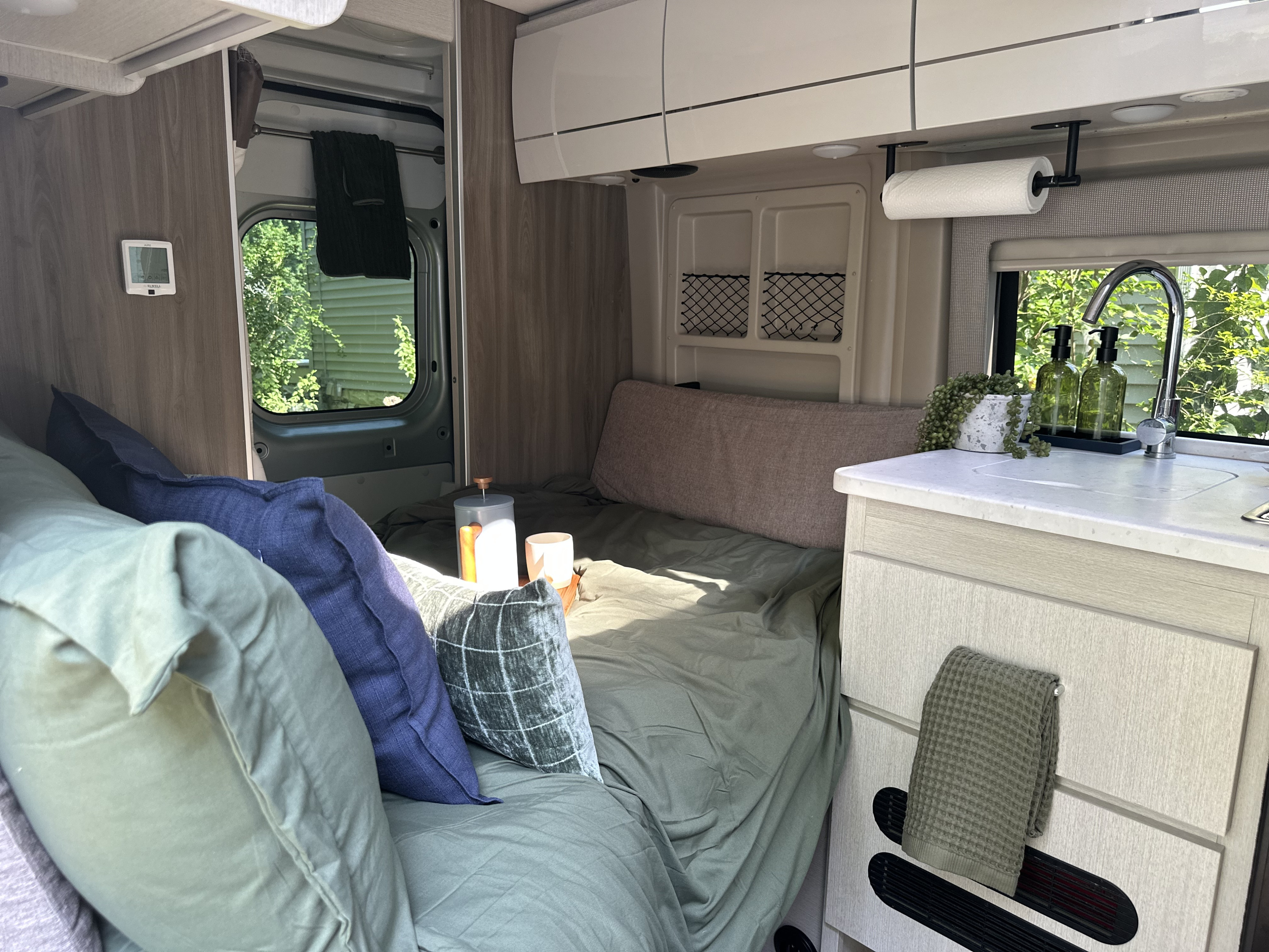 Enjoy this inviting RV rental interior, featuring a cozy bed, compact kitchen, and travel essentials like coffee.. Thor Motor Coach Rize 18G pop top 2024