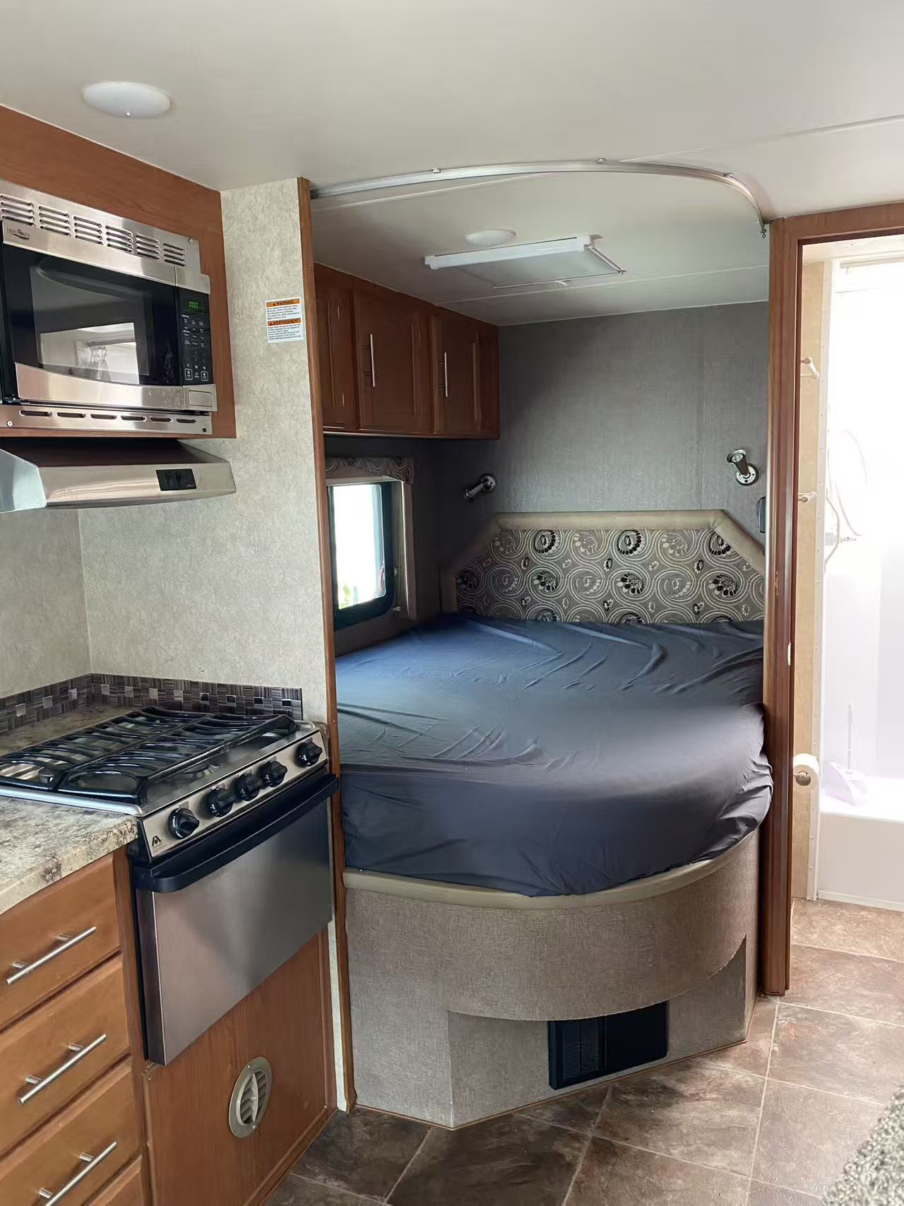 RV rental interior: Kitchen with microwave, stovetop; cozy bedroom with bed, patterned headboard. Functional and compact.. Adventurer Adventurer Motorhome 2016