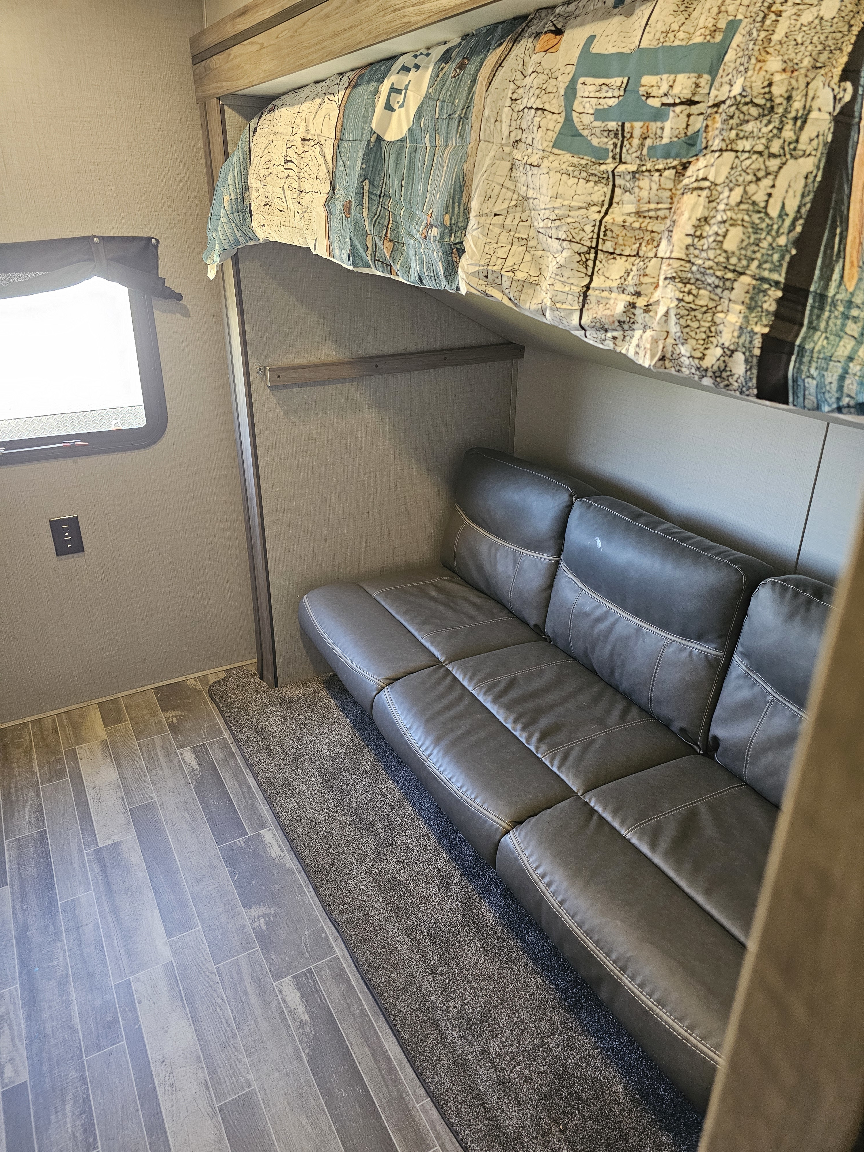 RV rental: interior with cozy bunk bed above a plush gray sofa, mixed flooring, and a window for natural light.. KZ Sportsman 2022
