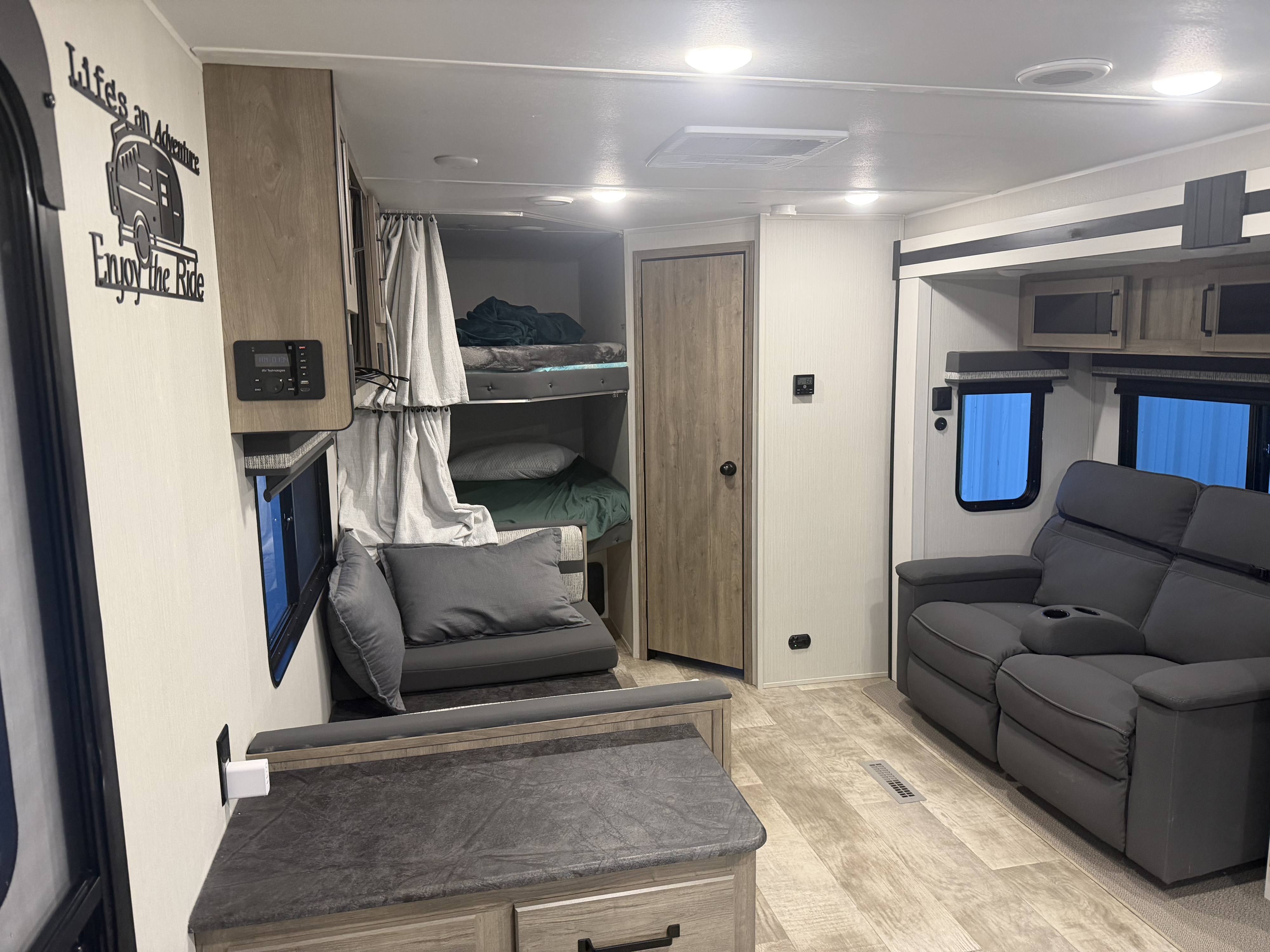 RV rental: Modern travel trailer interior with cozy bunk beds, recliner sofa, and a dinette. Perfect for family adventures.. Forest River Palomino Puma 2024