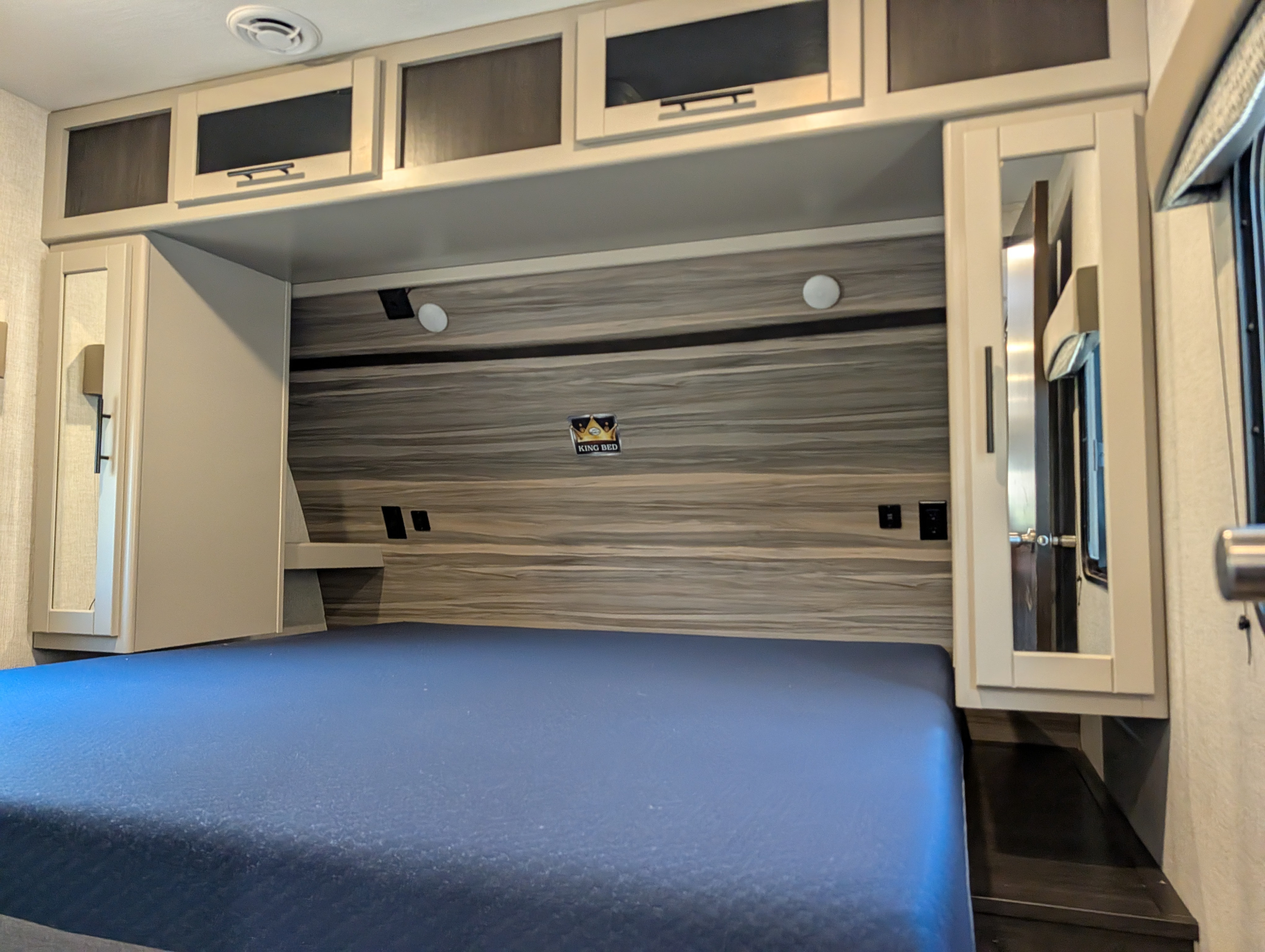 RV rental bedroom features a king bed with blue mattress, overhead storage, and side cabinets for comfortable travel.. Crossroads RV Cruiser Aire 2022