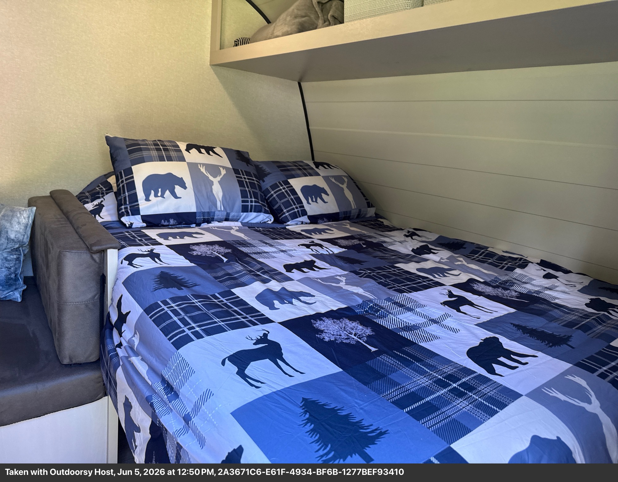 Cozy RV rental sleeping area: bed with blue plaid, bear, and deer nature-themed bedding, and two matching pillows.. Jayco Jay Feather Air SL 2025